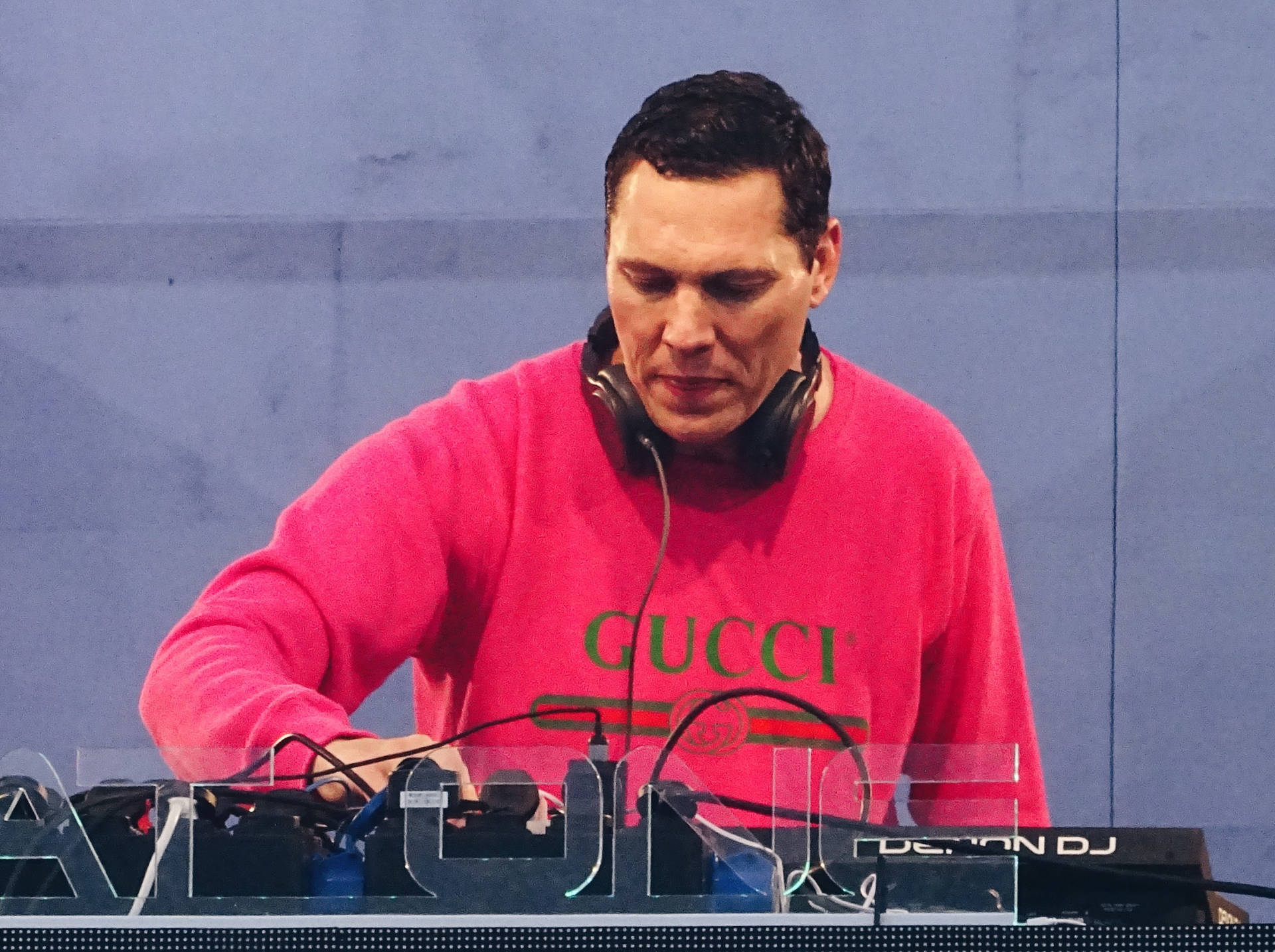 穿著粉紅色gucci衛衣的DJ在舞台上操作設備。