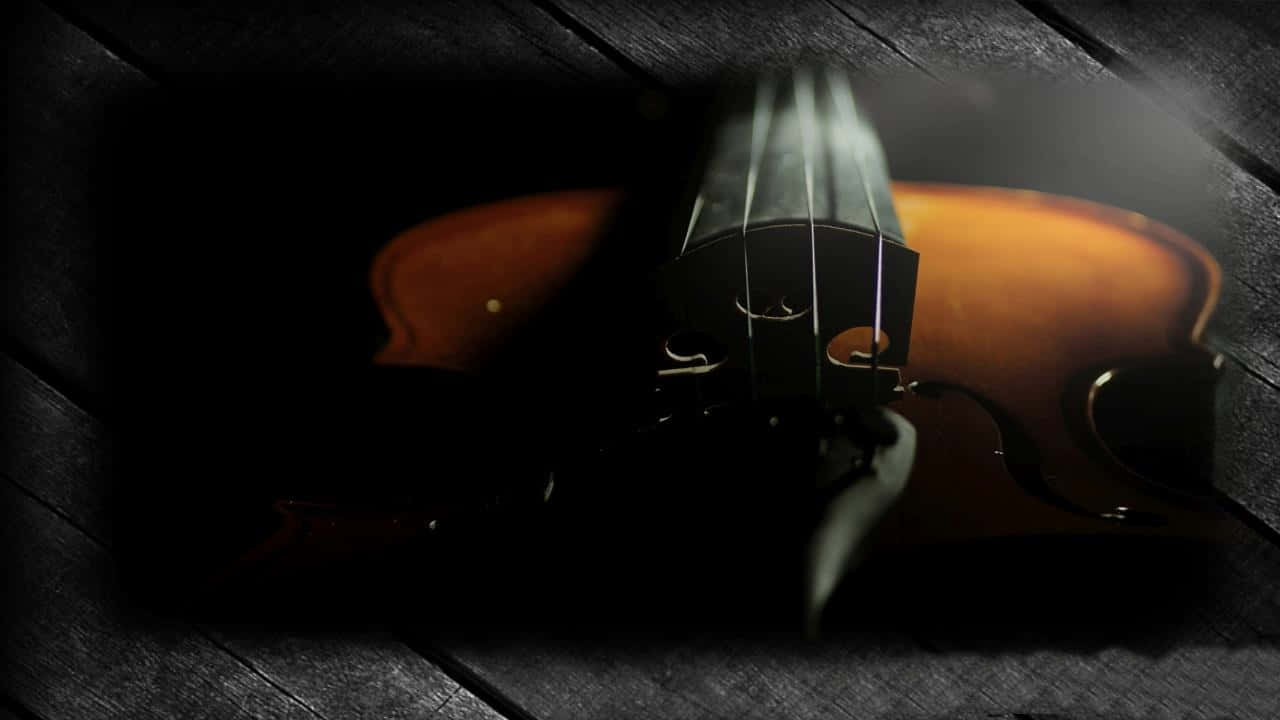 一把小提琴在深色木質表面上被光照亮。