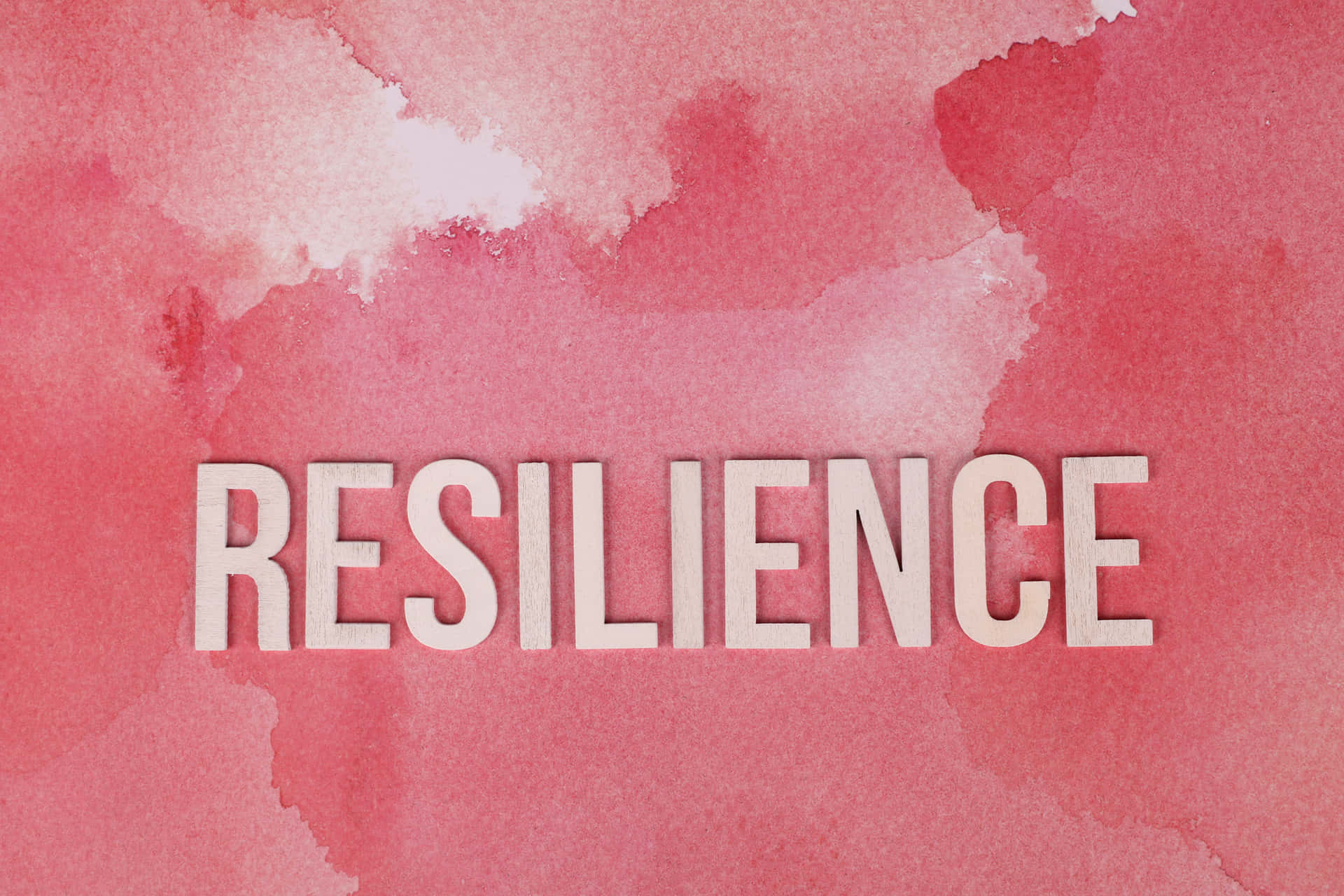 粉紅色水彩背景上白色字體的「resilience」一詞。