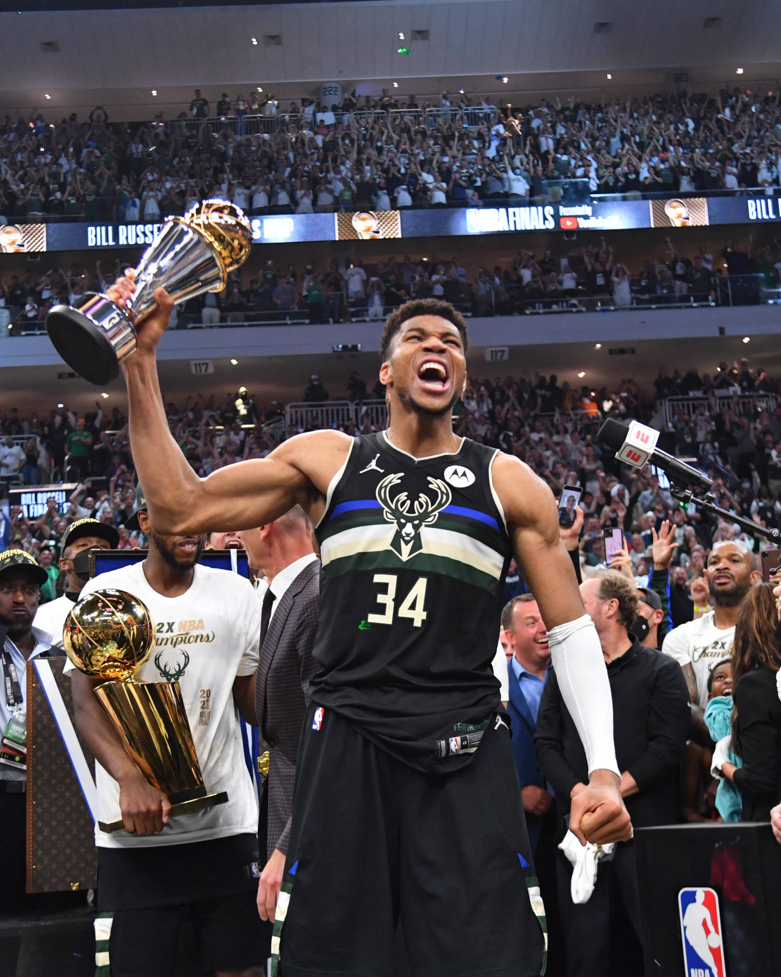 籃球運動員在球場中手持NBA總冠軍獎盃，周圍有群眾