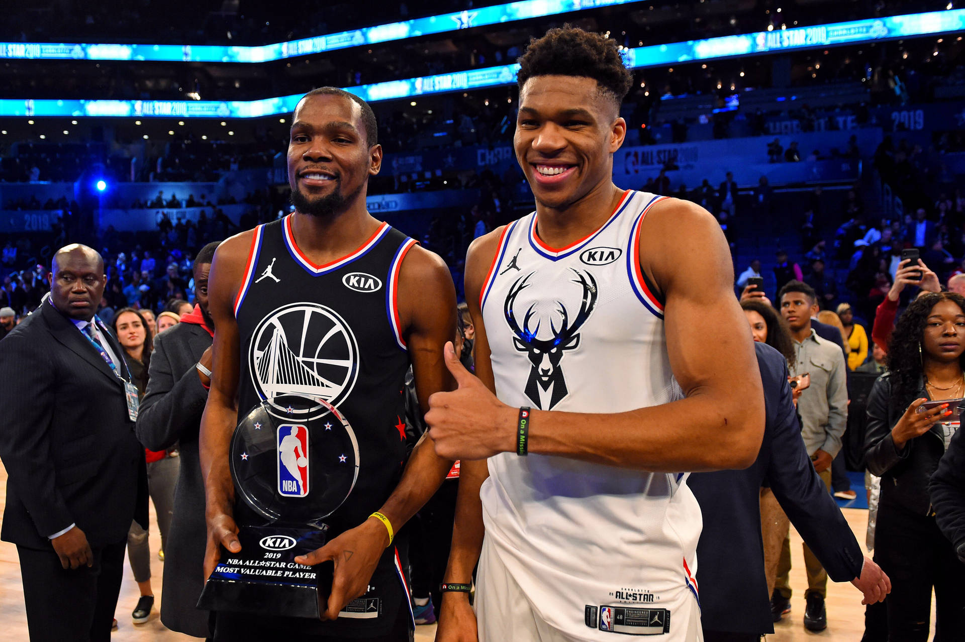 兩位籃球運動員在球場上微笑並與獎項合影。