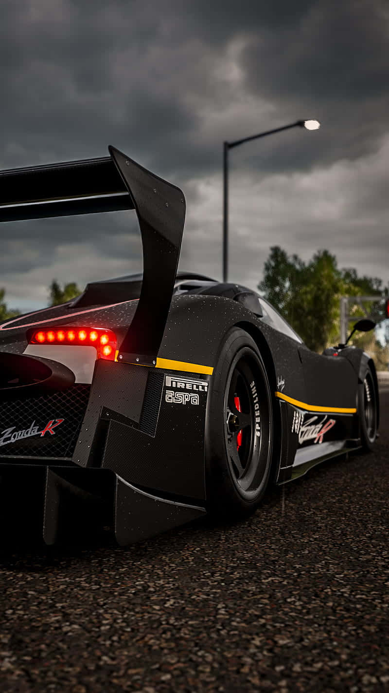 握緊方向盤，以時尚姿態飆速 壁紙 — 一輛黑色Zonda R跑車，紅色尾燈發光，停在暴風雨天空下的瀝青路面上。