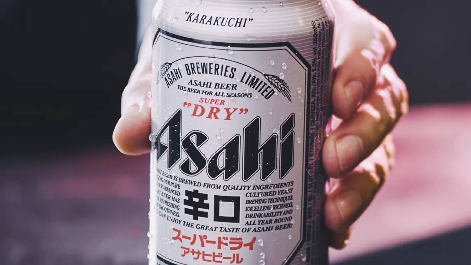 手握住帶有冷凝水珠的冰凍朝日超乾啤酒罐。