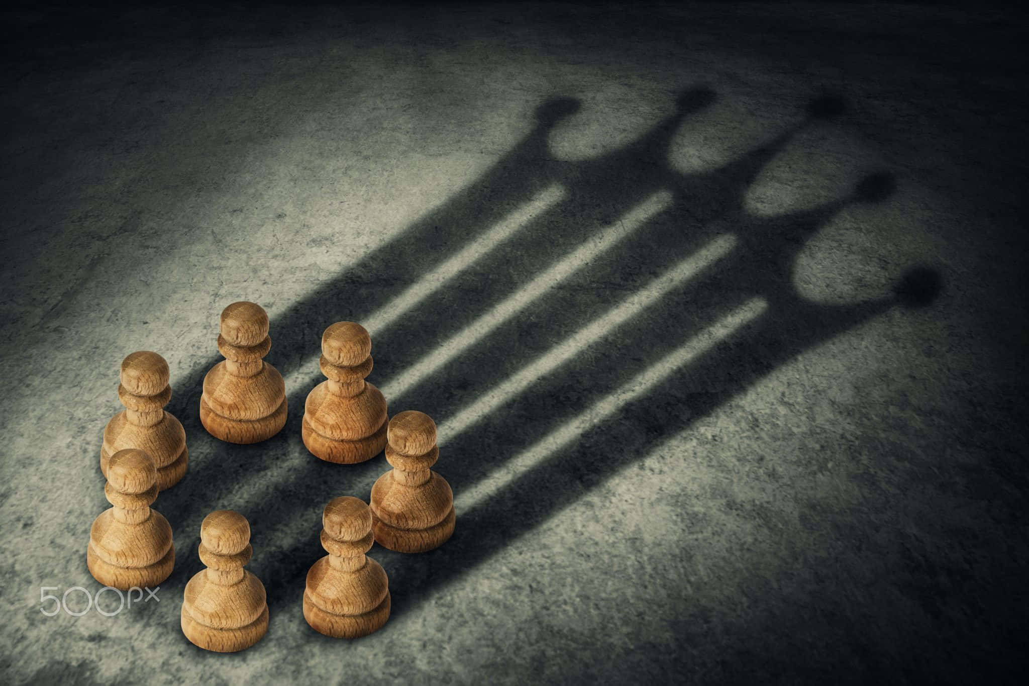揭開象棋策略的奧秘 壁紙 — 木製國際象棋兵在聚焦燈光下，在粗糙的混凝土地板上投射出戲劇性的皇冠陰影。