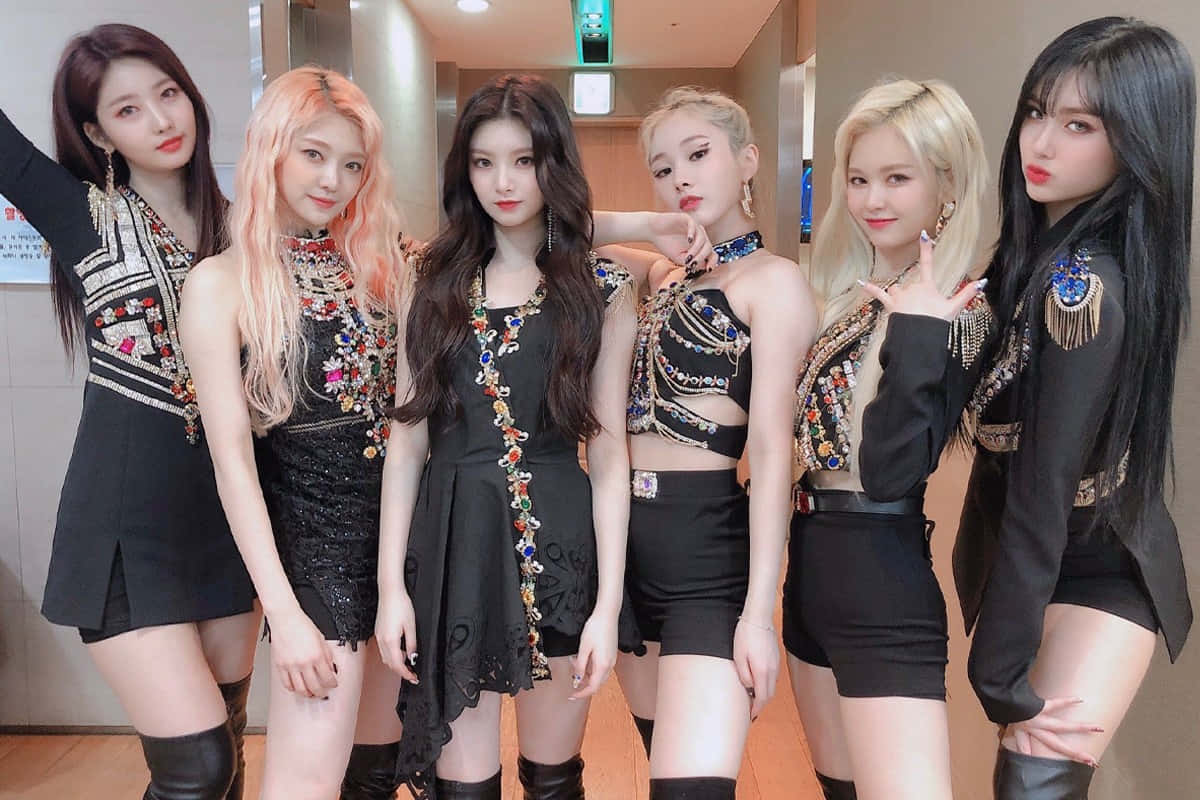 六位女性K-pop偶像穿著黑色閃亮服裝在室內擺姿勢。