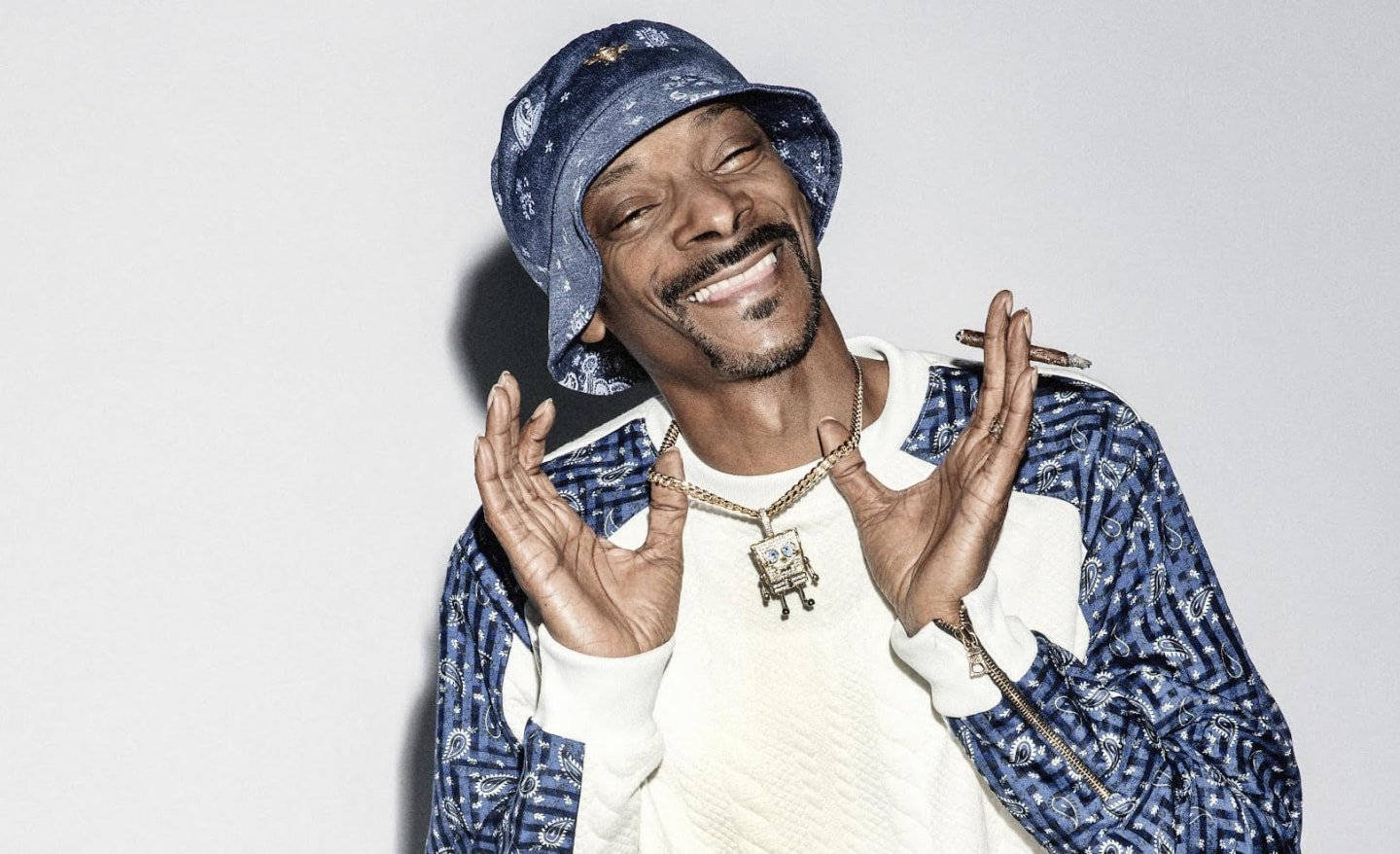 Snoop Dogg 微笑，身穿藍色圖案服裝，戴著金鏈。