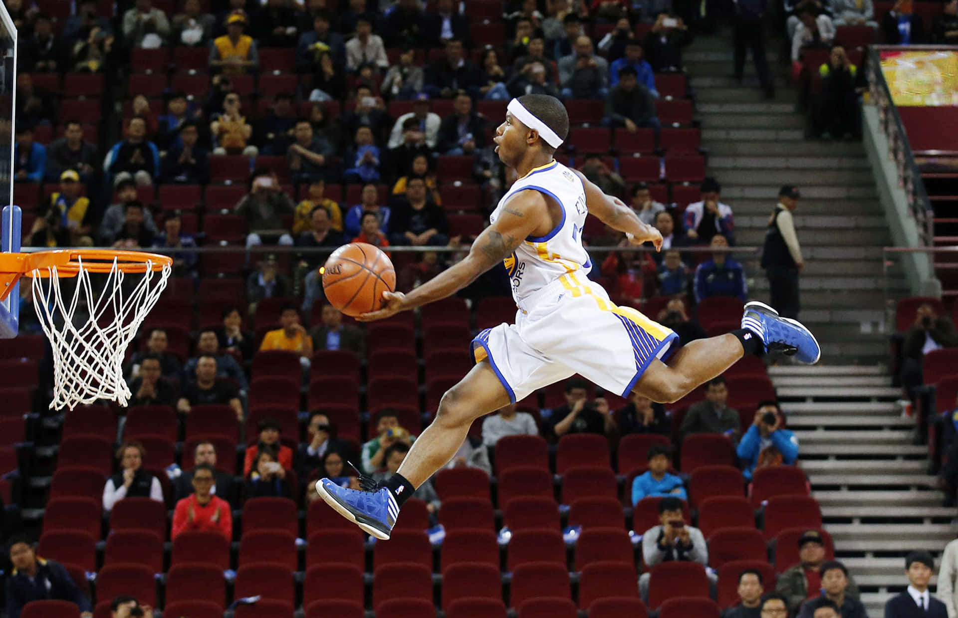 搞笑NBA高跳圖片 壁紙 — 一名身穿白色和藍色球衣的籃球運動員在比賽中全神貫注地跳向籃框。