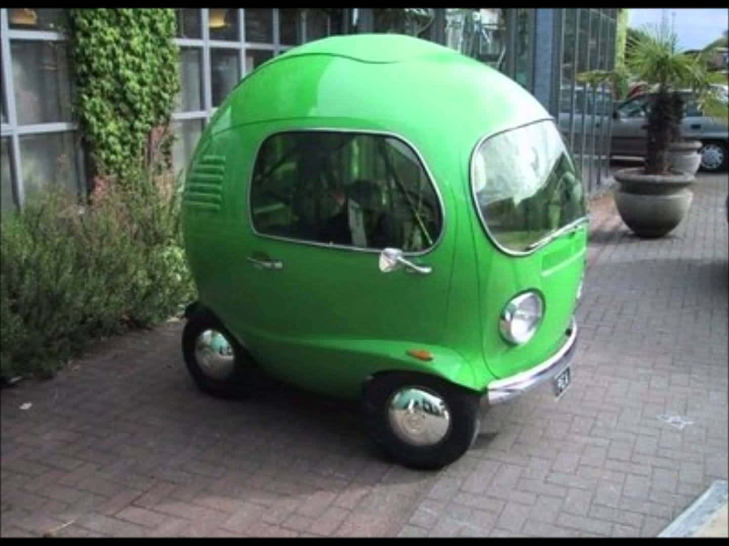 一架綠色蛋形復古車停在磚砌行人路上。