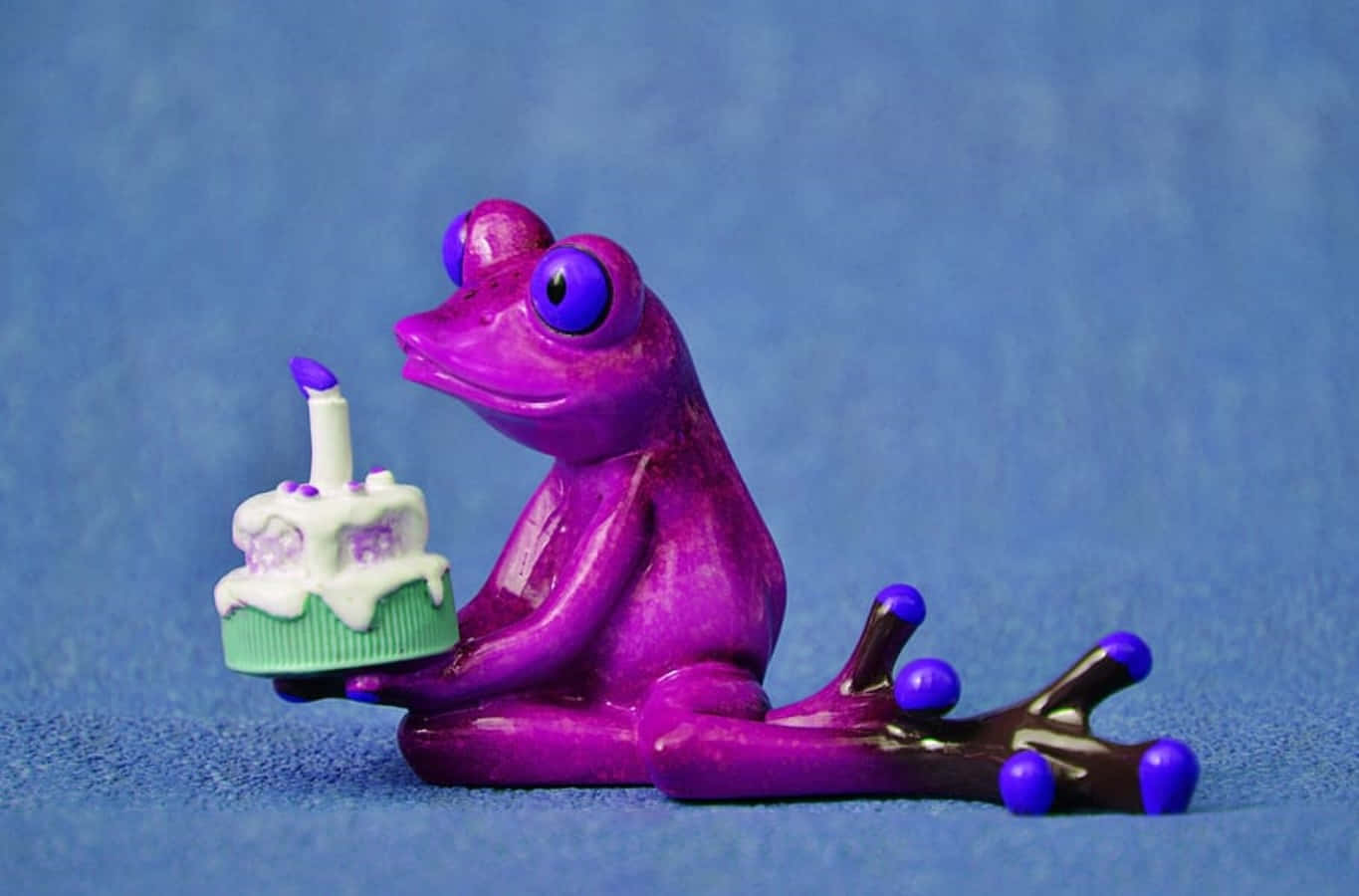 紫色青蛙公仔手持生日蛋糕，蛋糕上有一支蠟燭。