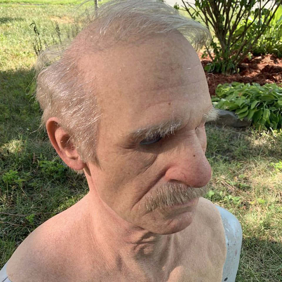 搞笑老翁酷炫面具圖 壁紙 — 一位灰白頭髮和鬍子的老年男子特寫，戶外明亮日光下。