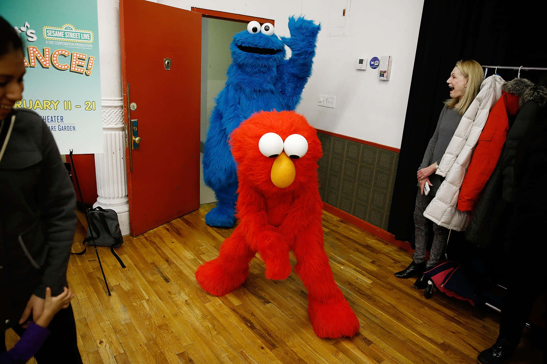 穿著服裝的 Elmo 和 Cookie Monster 在劇院後台向粉絲打招呼。