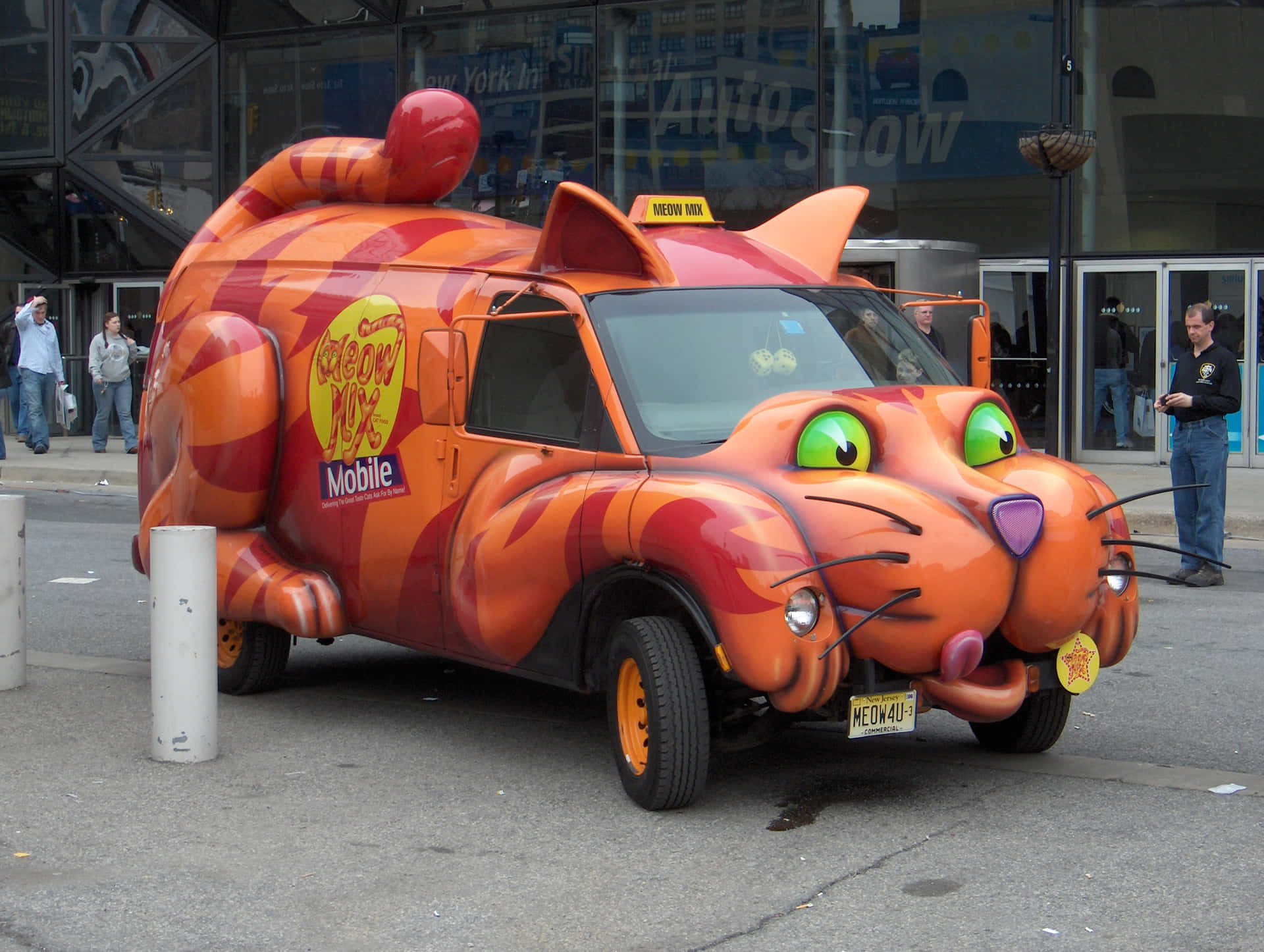 一輛卡通貓出租車，有綠色眼睛和粉紅色舌頭，停在城市街道上。