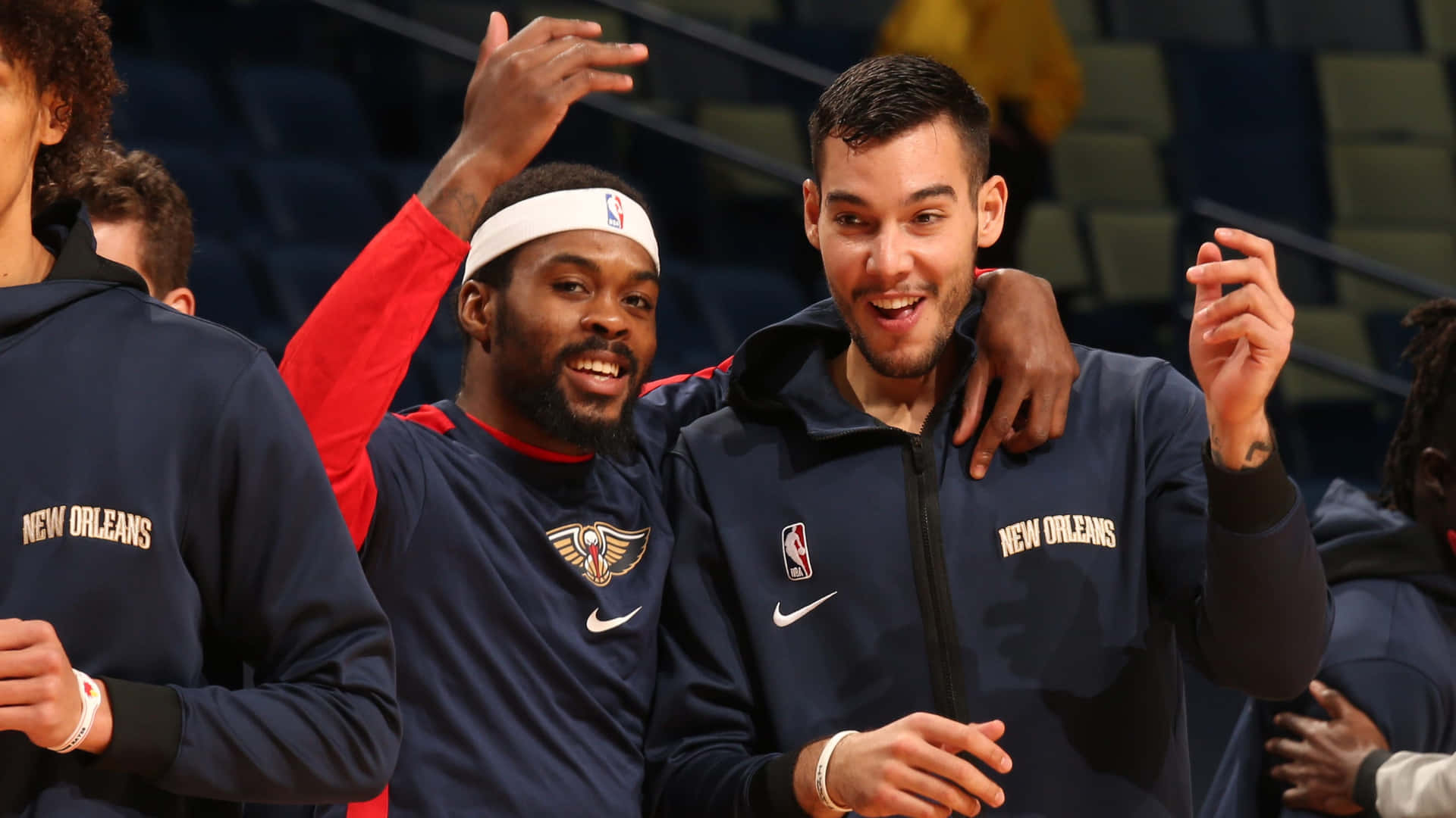 搞笑開心NBA球員圖片 壁紙 — 兩位身穿海軍藍熱身服的新奧爾良鵜鶘籃球運動員微笑著在球場上舉手慶祝。