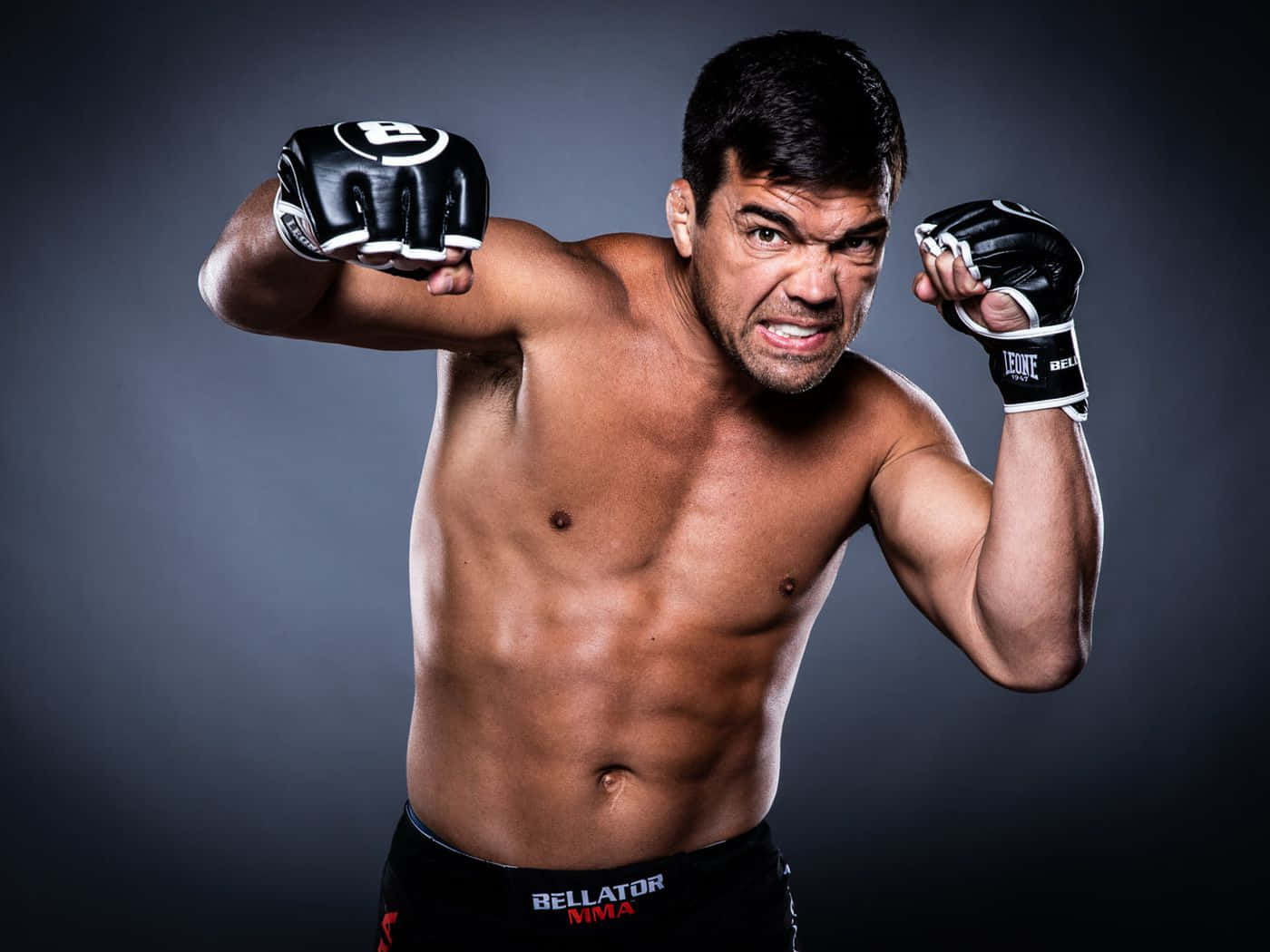 一位赤裸上身的男性MMA拳擊手，戴著黑色手套和Bellator短褲，在工作室中激烈擺姿勢。