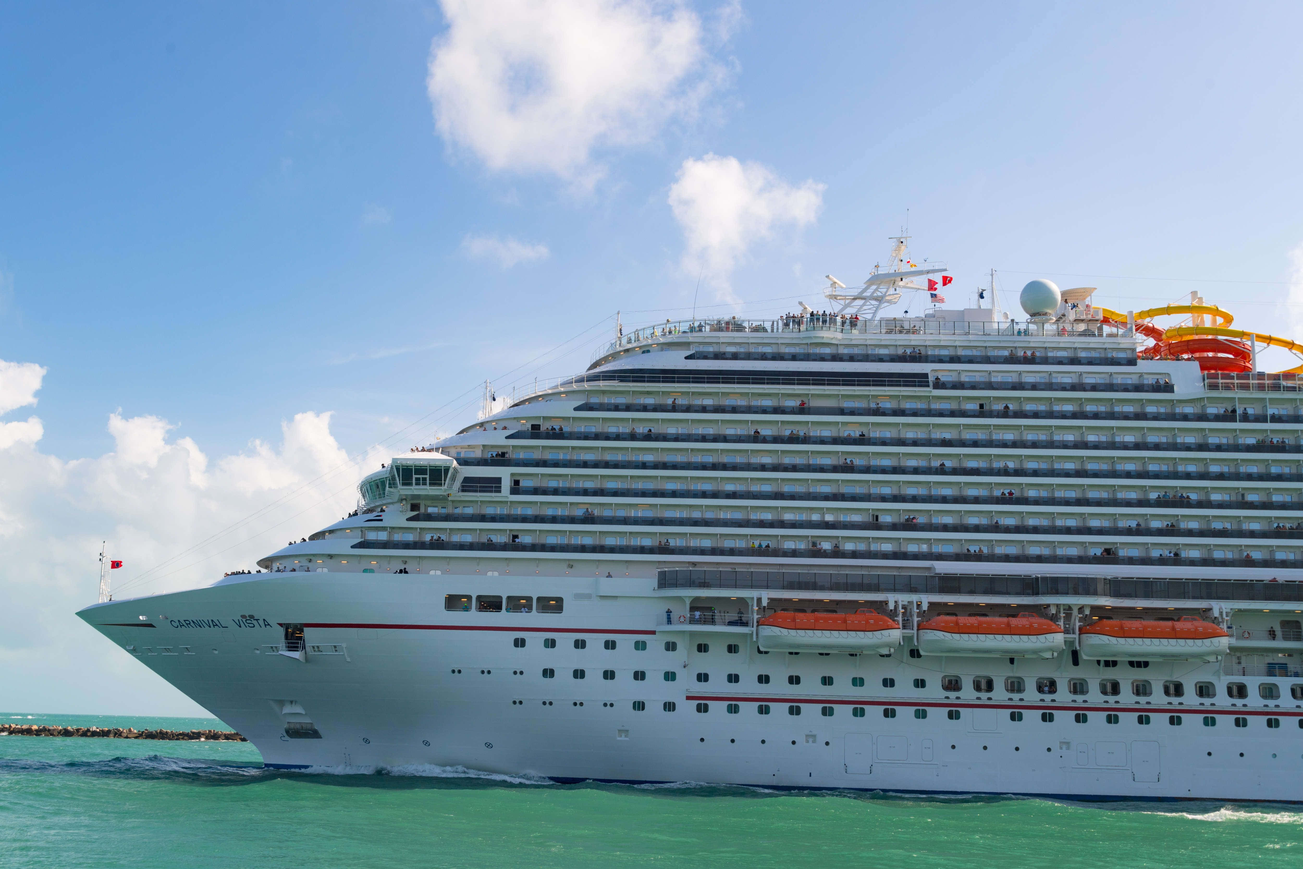 搭乘Carnival Dream號，體驗天堂般的旅程 壁紙 — 一艘名為 Carnival Vista 的巨型白色郵輪在蔚藍的天空和蓬鬆雲朵下，航行於碧綠色的水域中。