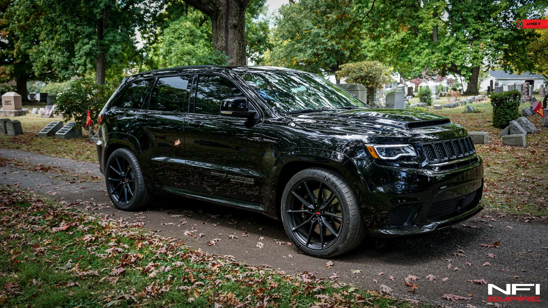 黑色Jeep SUV停泊在墓園小徑上，有落葉和墓碑。