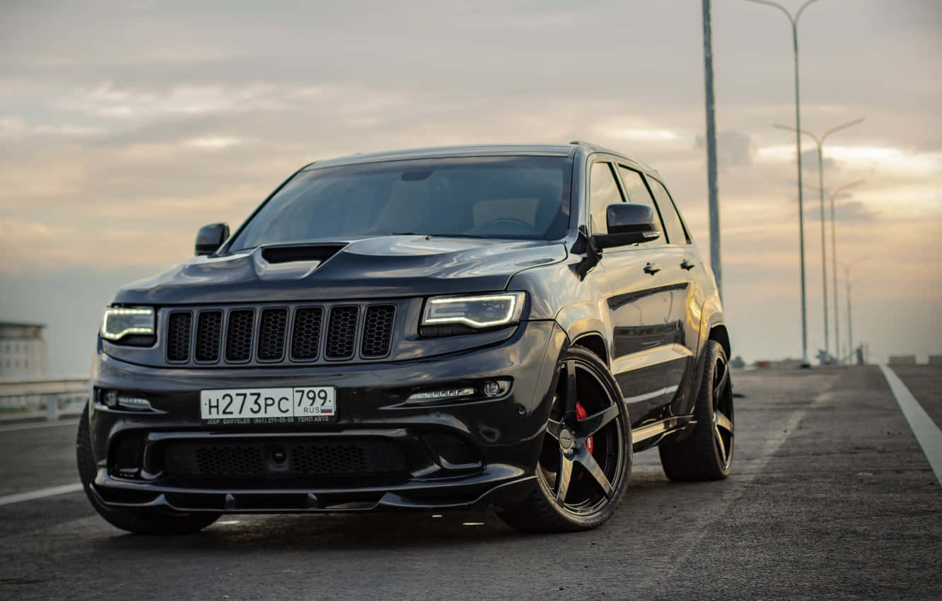 日落時分高速公路上帶紅色制動卡鉗的黑色Jeep Grand Cherokee SRT。