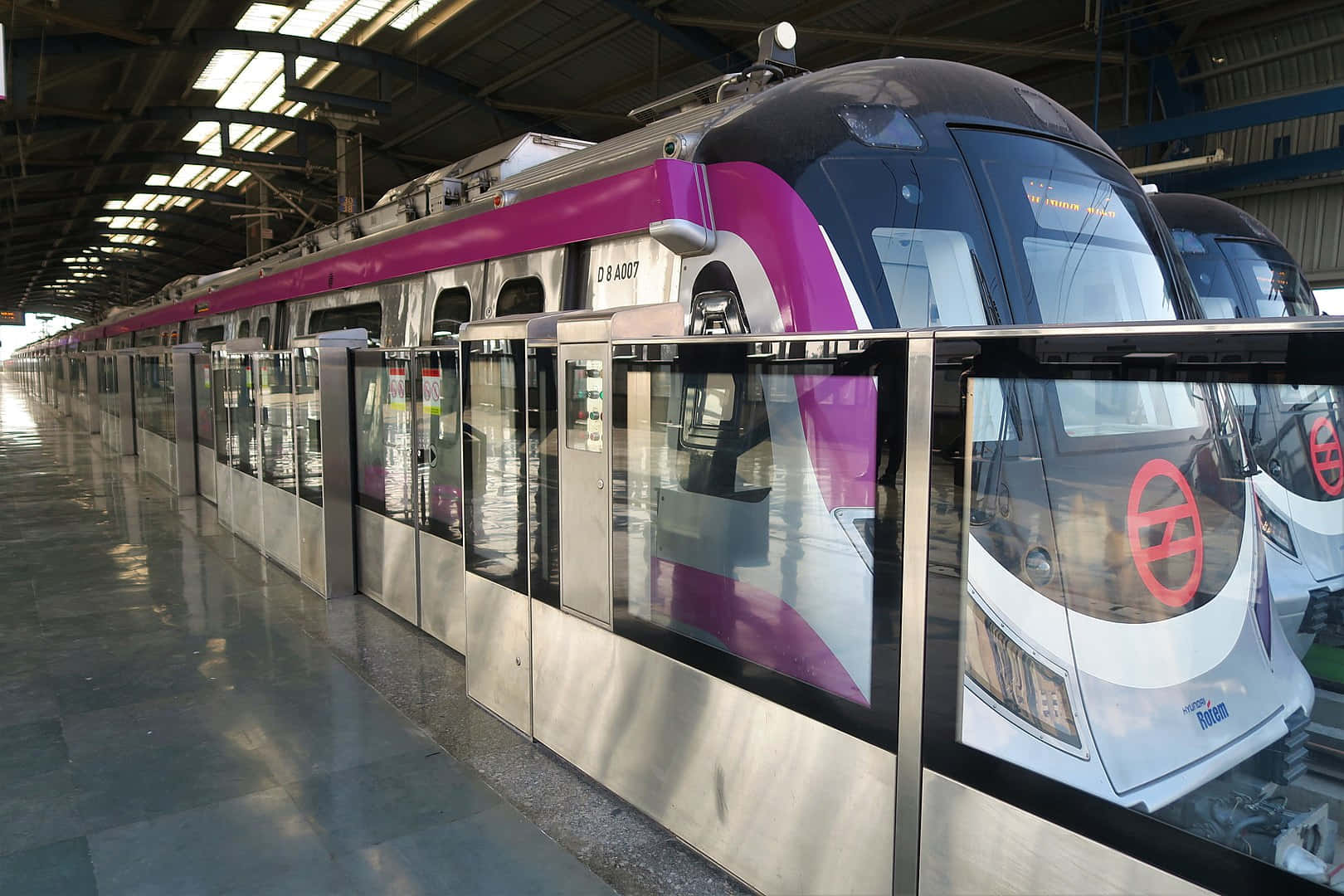 現代紫色和銀色地鐵列車停放在有蓋車站內，地板具有反射效果。