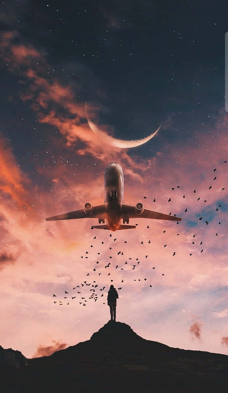 山頂上的人看著飛機在暮色中彎月下飛行。