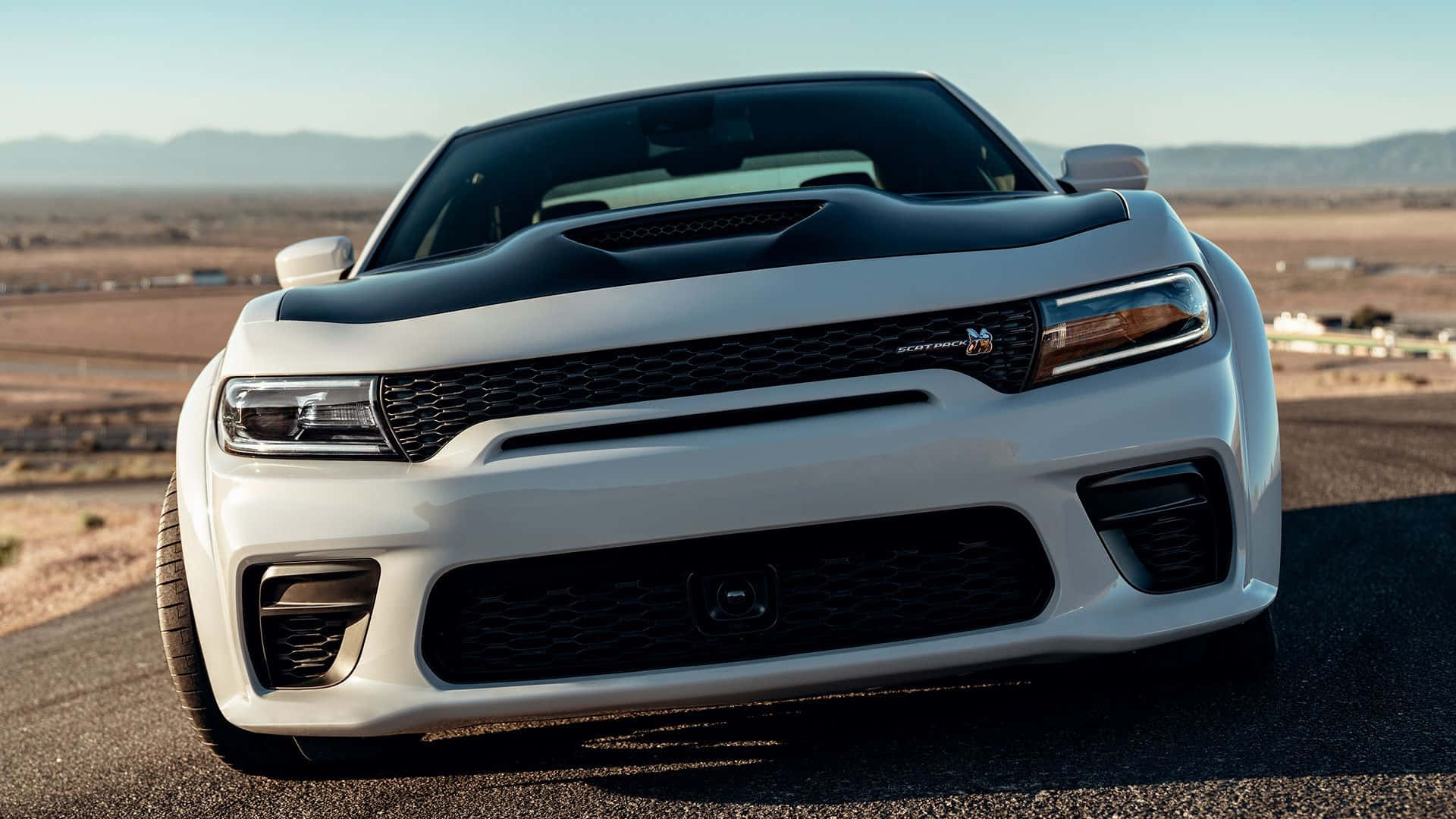 白色Dodge Challenger SRT Hellcat在沙漠公路上，背景有山。