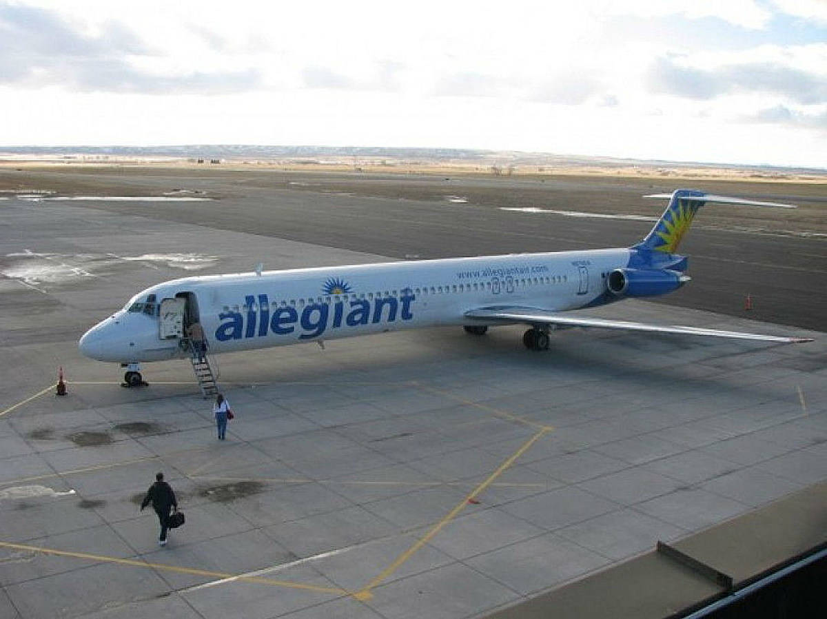 Allegiant Air 飛機停在停機坪，人們正在登機並攜帶行李行走。
