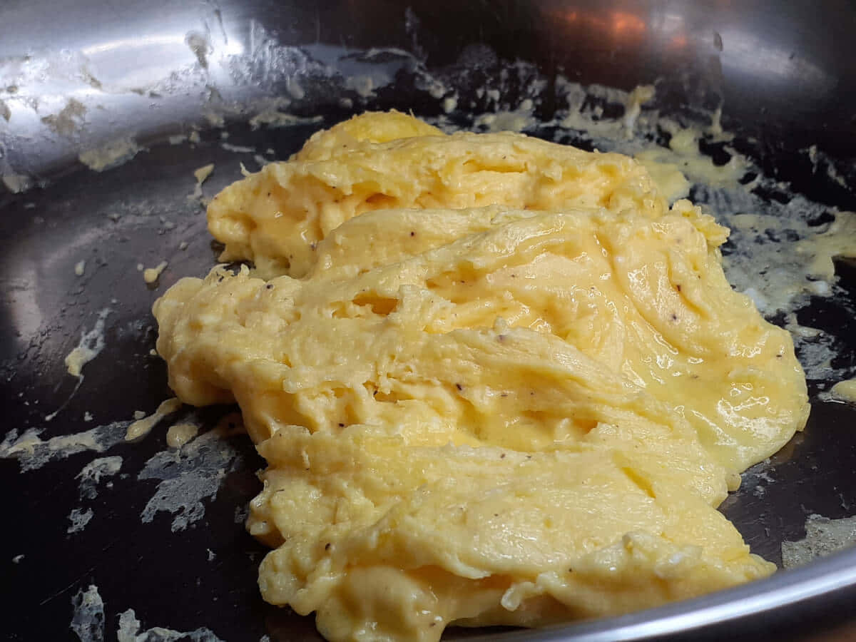 搭配吐司與火腿的美味炒蛋 壁紙 — 金黃色 fluffy 炒蛋配黑胡椒，在一個用得很多的 stainless steel 煎 pan 中滋滋作響。
