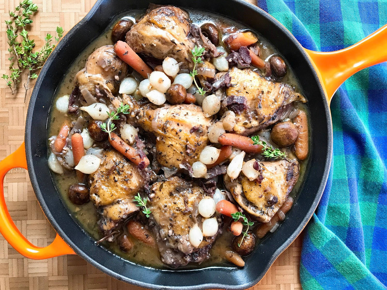 搭配珍珠洋蔥的正宗Coq Au Vin 壁紙 — 一鍋豐盛的雞大腿，與胡蘿蔔、珍珠洋蔥、蘑菇和百里香在濃郁醬汁中慢燉。