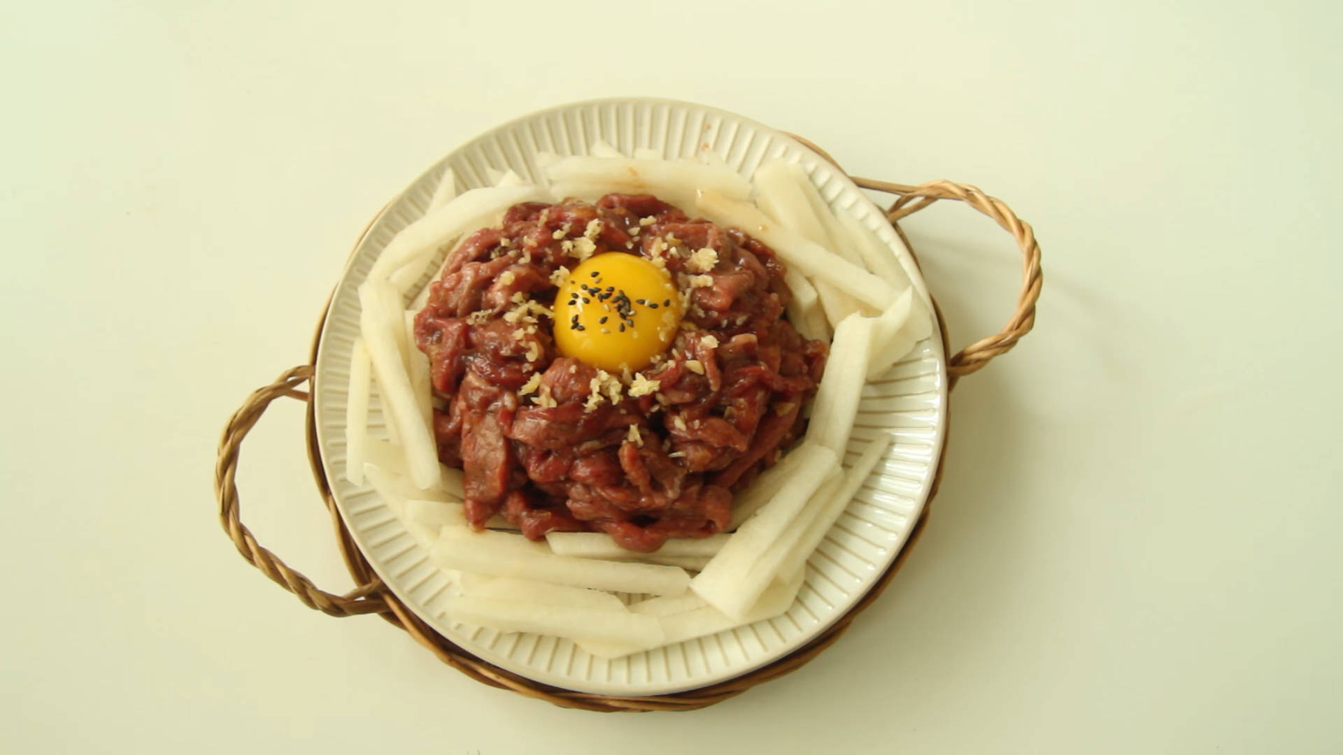 搭配蛋黃的牛排塔塔 壁紙 — 一碗生牛肉他他，上面放著生蛋黃，並以黑胡椒和蒜末裝飾。