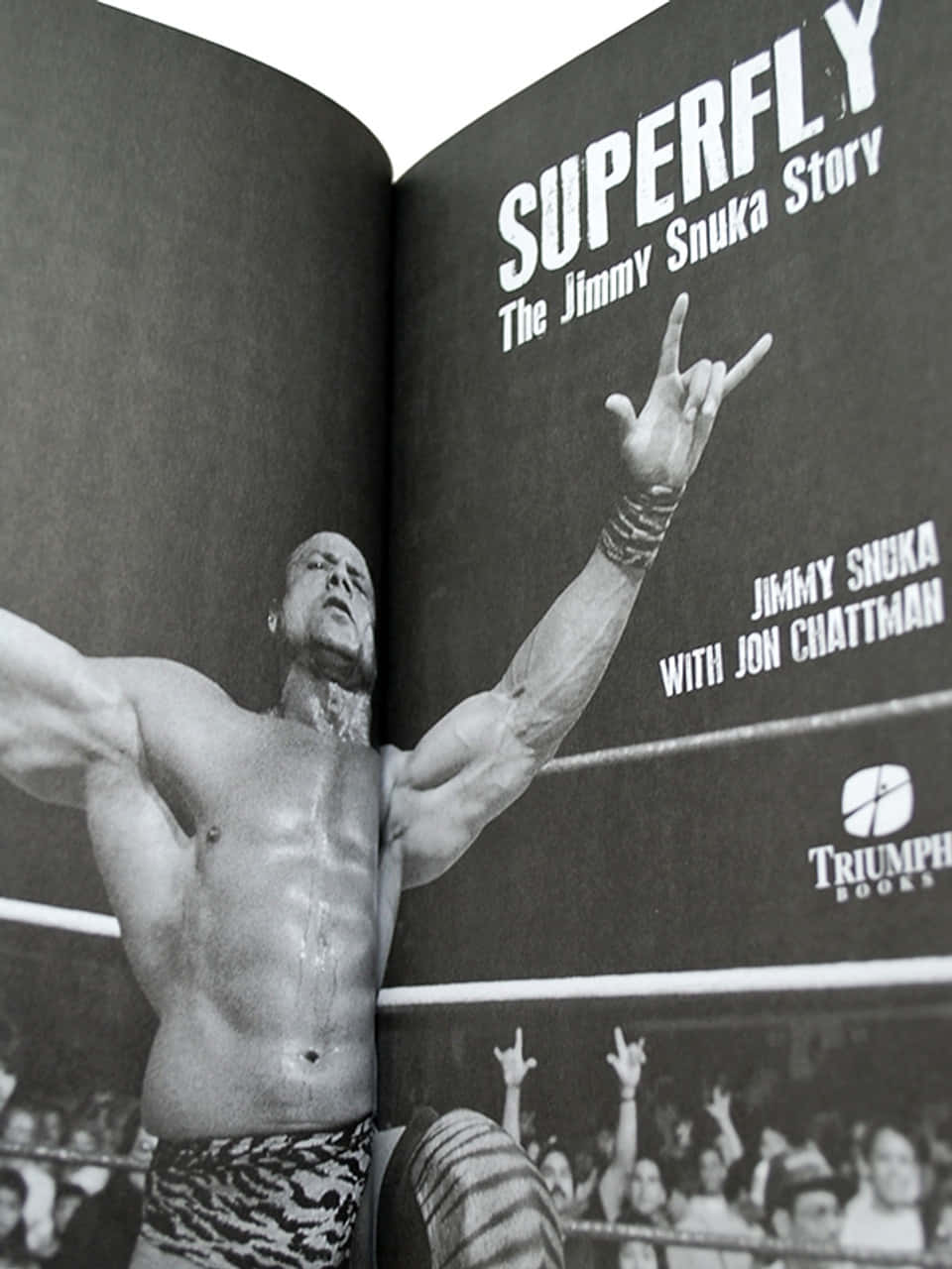 摔角手 Jimmy Snuka 在擂台上做出搖滾手勢，群眾歡呼。