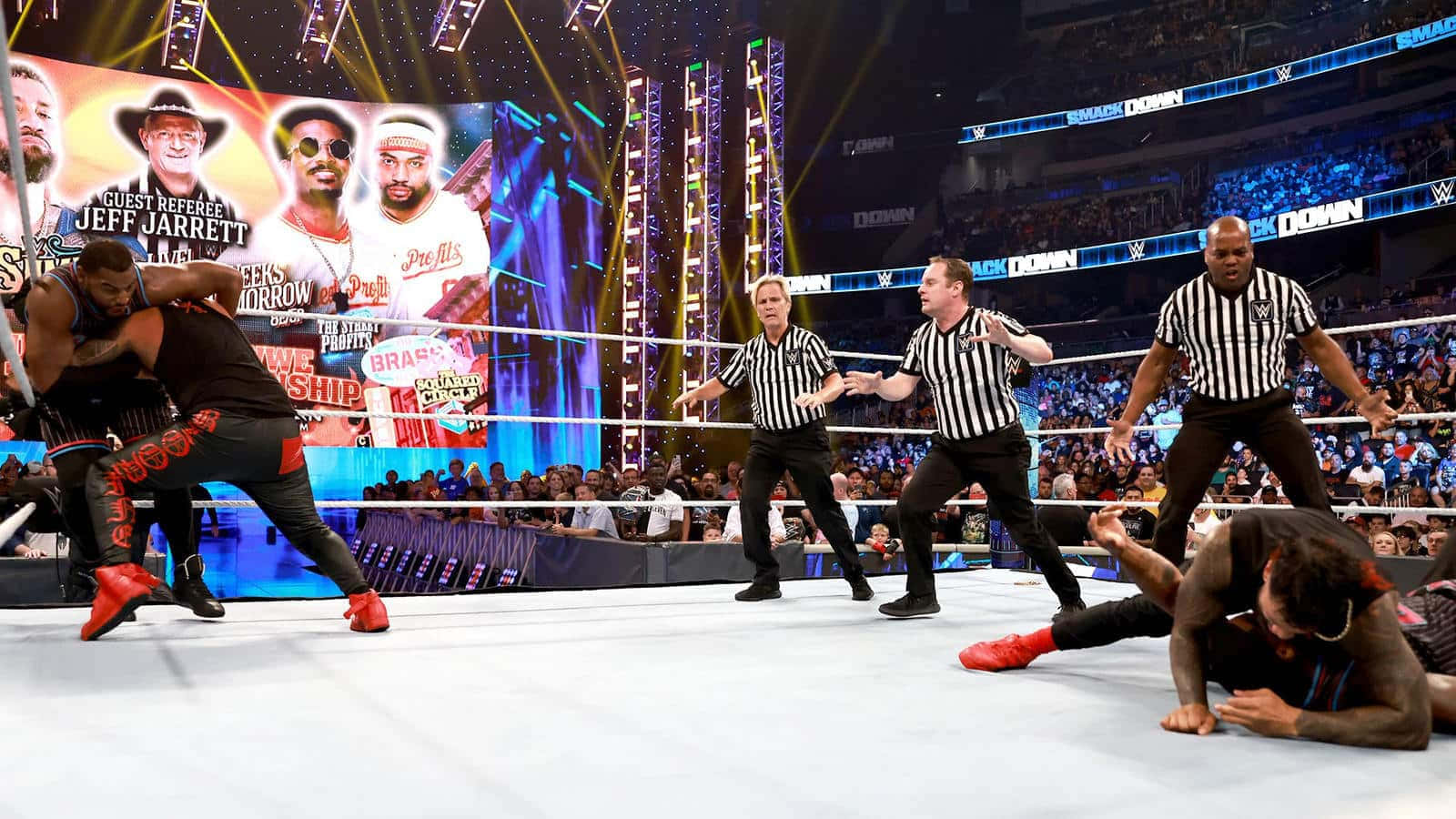 摔角巨星傑夫·賈雷特參加 Smackdown Rumble 比賽 壁紙 — 摔角手在燈光明亮的擂台上戰鬥，裁判在WWE活動中於咆哮的人群中干預。