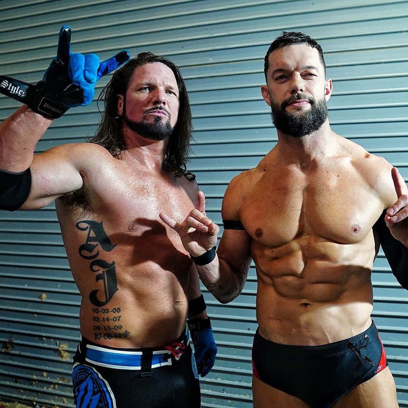 摔角手AJ Styles與Finn Balor 壁紙 — 兩名肌肉發達的摔角手自信地靠在波紋金屬牆上，身上有紋身並穿著摔角裝備。