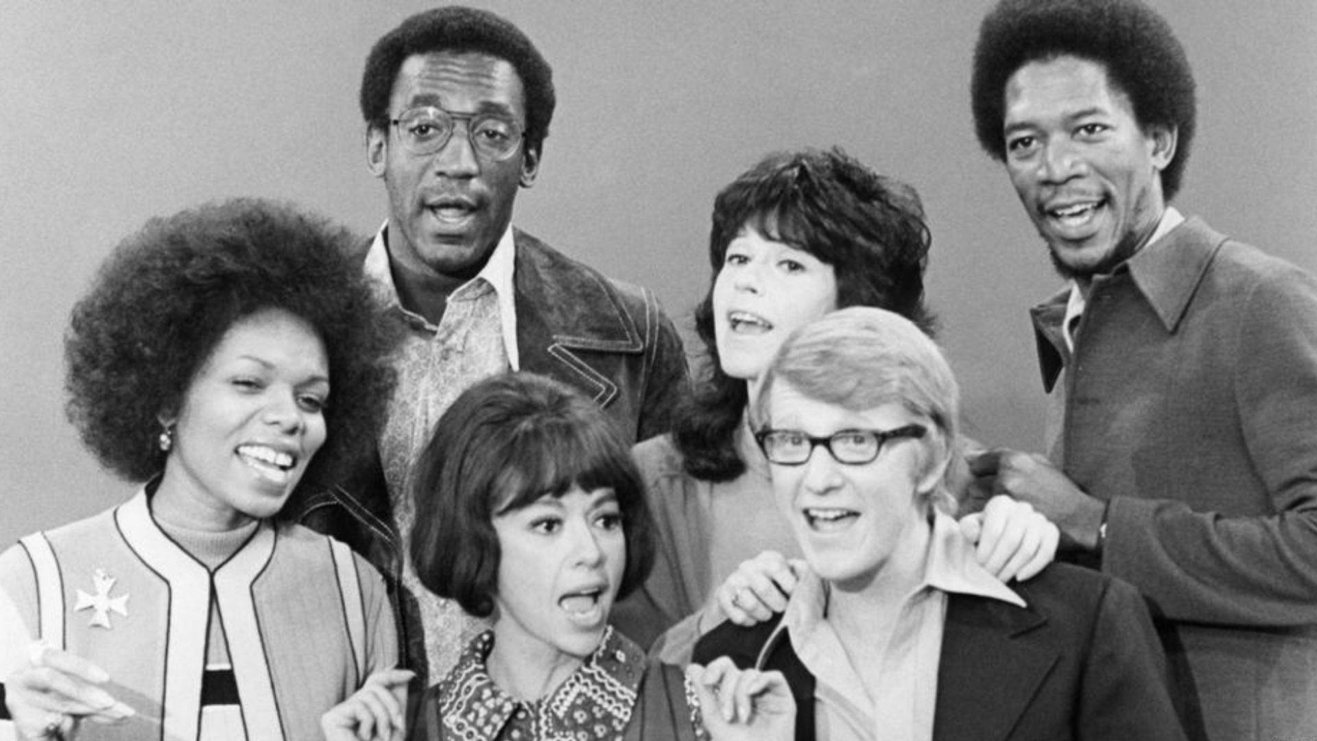 摩根·弗里曼在《電力公司》 壁紙 — 一張1970年代電視節目《Soul Train》中六位微笑演員一起擺姿勢的黑白照片。