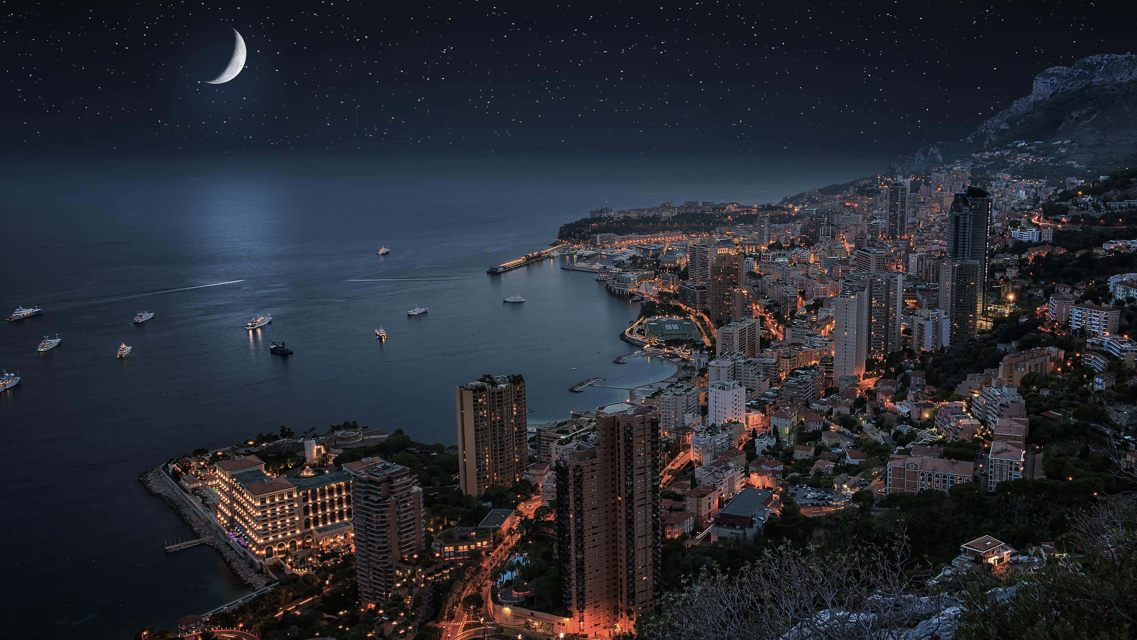 摩納哥夜景月色圖 壁紙 — 在星空下，摩納哥璀璨的海岸城市景觀，新月和船隻在平靜的海面上，令人嘆為觀止的夜景。