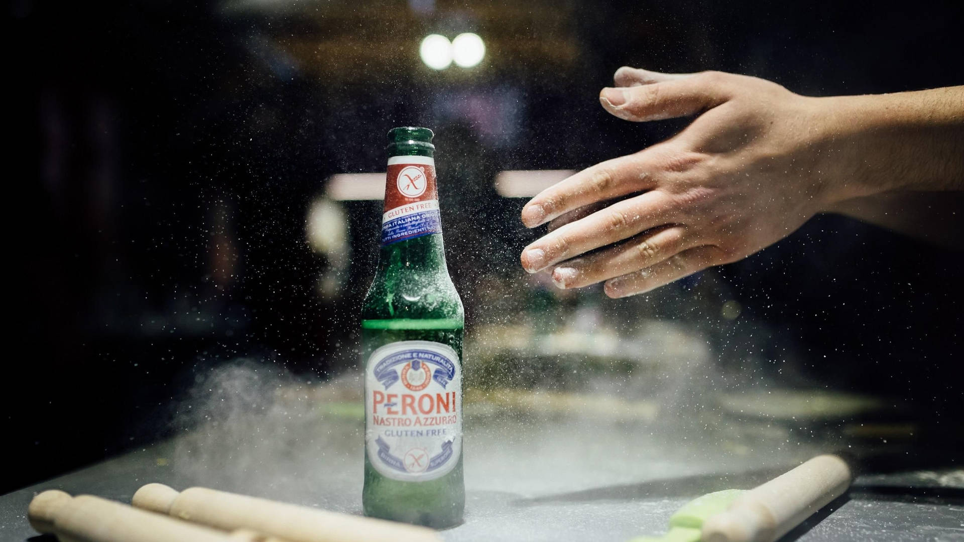 一隻手伸向被麵粉和擀麵棍包圍的 Peroni 啤酒瓶。