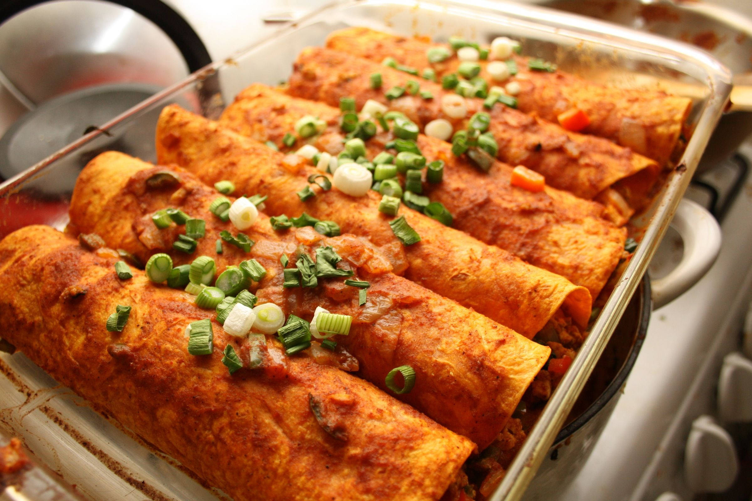 撒有青蔥的乾式 enchiladas 盤 壁紙 — 新鮮出爐的玉米捲餅放在玻璃盤中，上面撒有切碎的青蔥和融化的芝士。