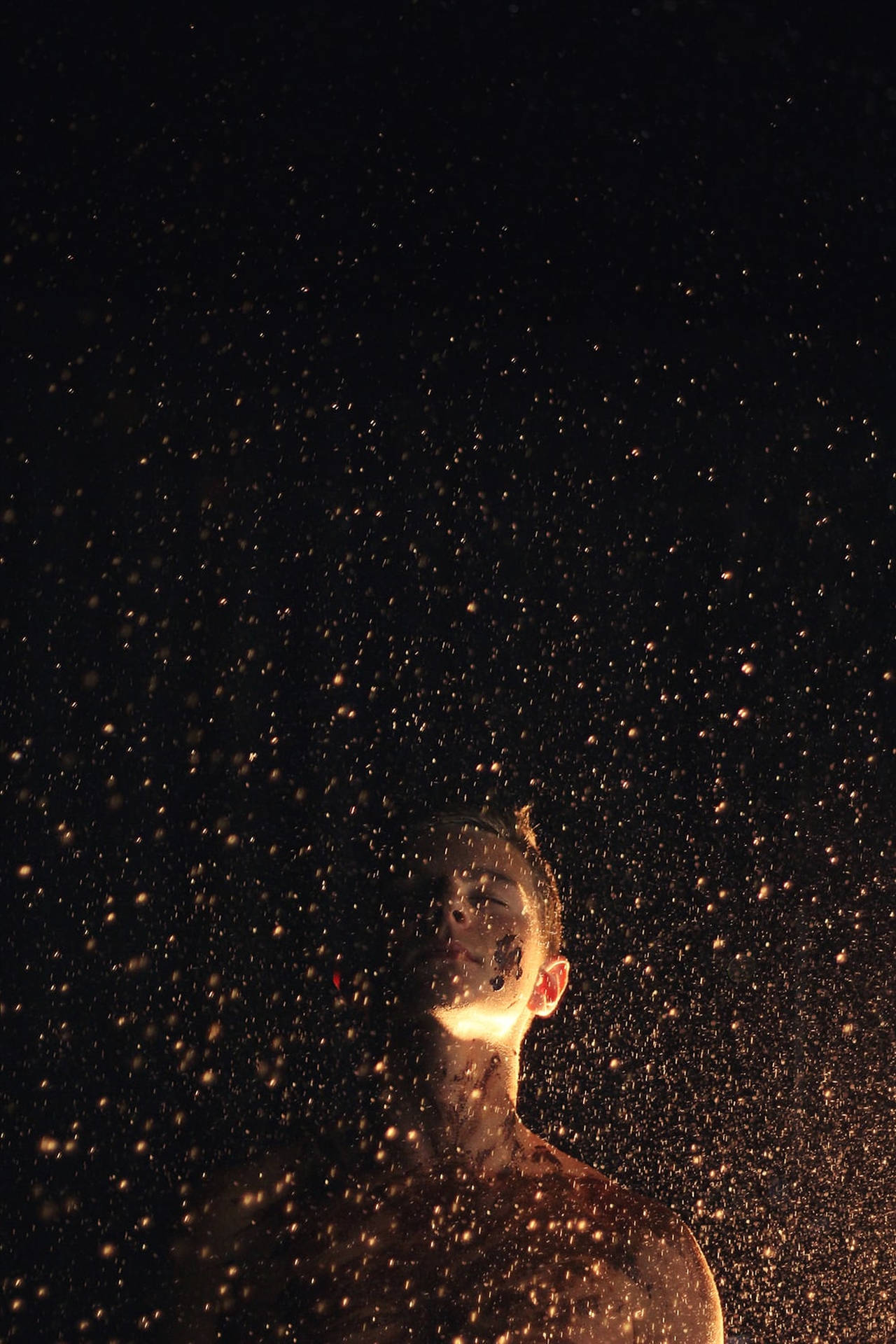 在黑暗背景中沐浴金色火花的人。