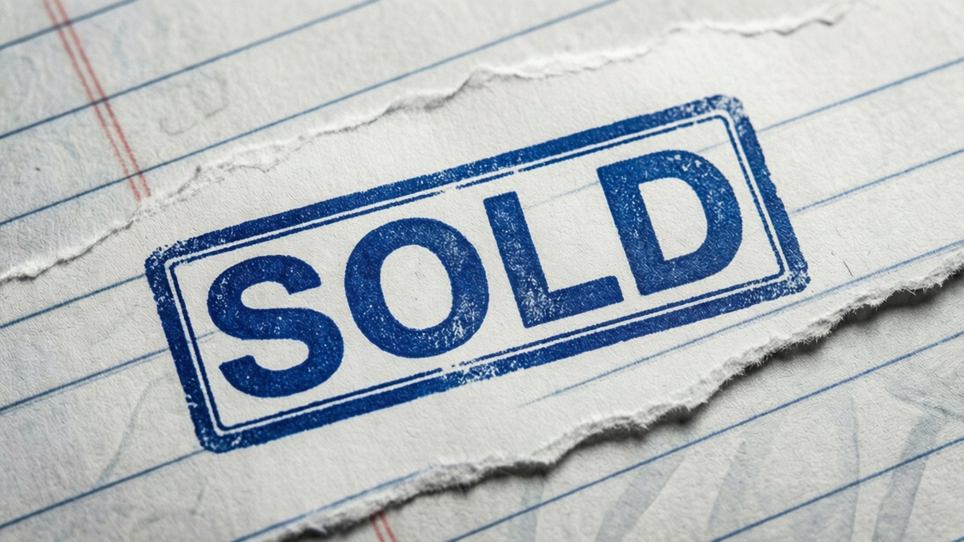 藍色「SOLD」印章在撕破的橫線筆記本紙上