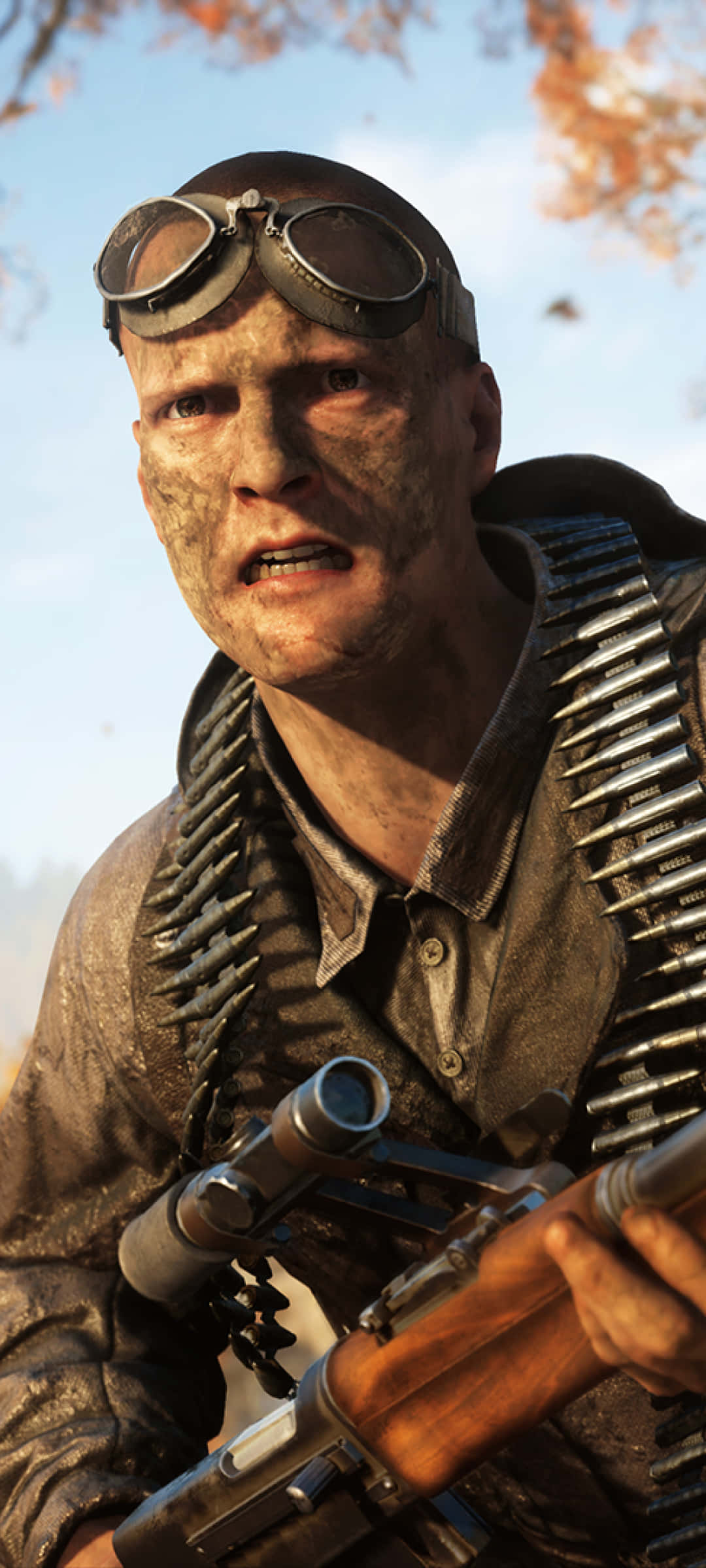 擁抱 Pixel 3XL 的強大效能，體驗 Battlefield V 的刺激 壁紙 — 一名骯髒的士兵戴著護目鏡和彈藥帶，在秋葉和晴朗天空的背景下凝視著。
