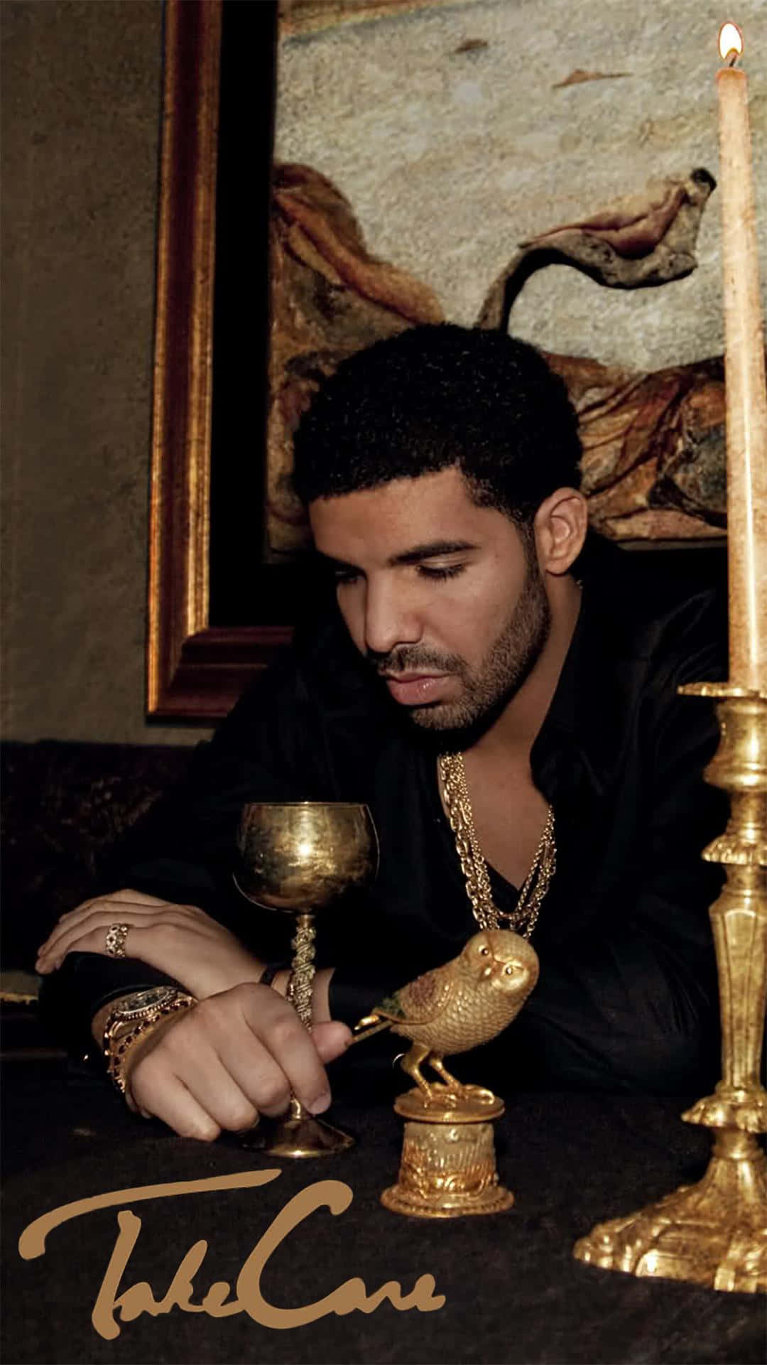 Drake 在黑暗的房間裡手持金色高腳杯，旁邊有蠟燭和貓頭鷹雕像。
