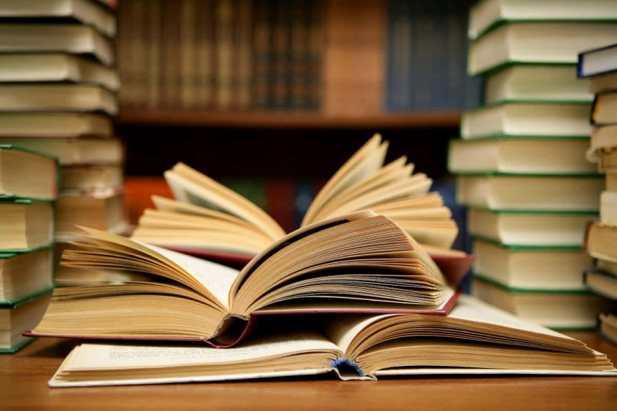 在圖書館的木桌上，打開的書被書堆環繞。