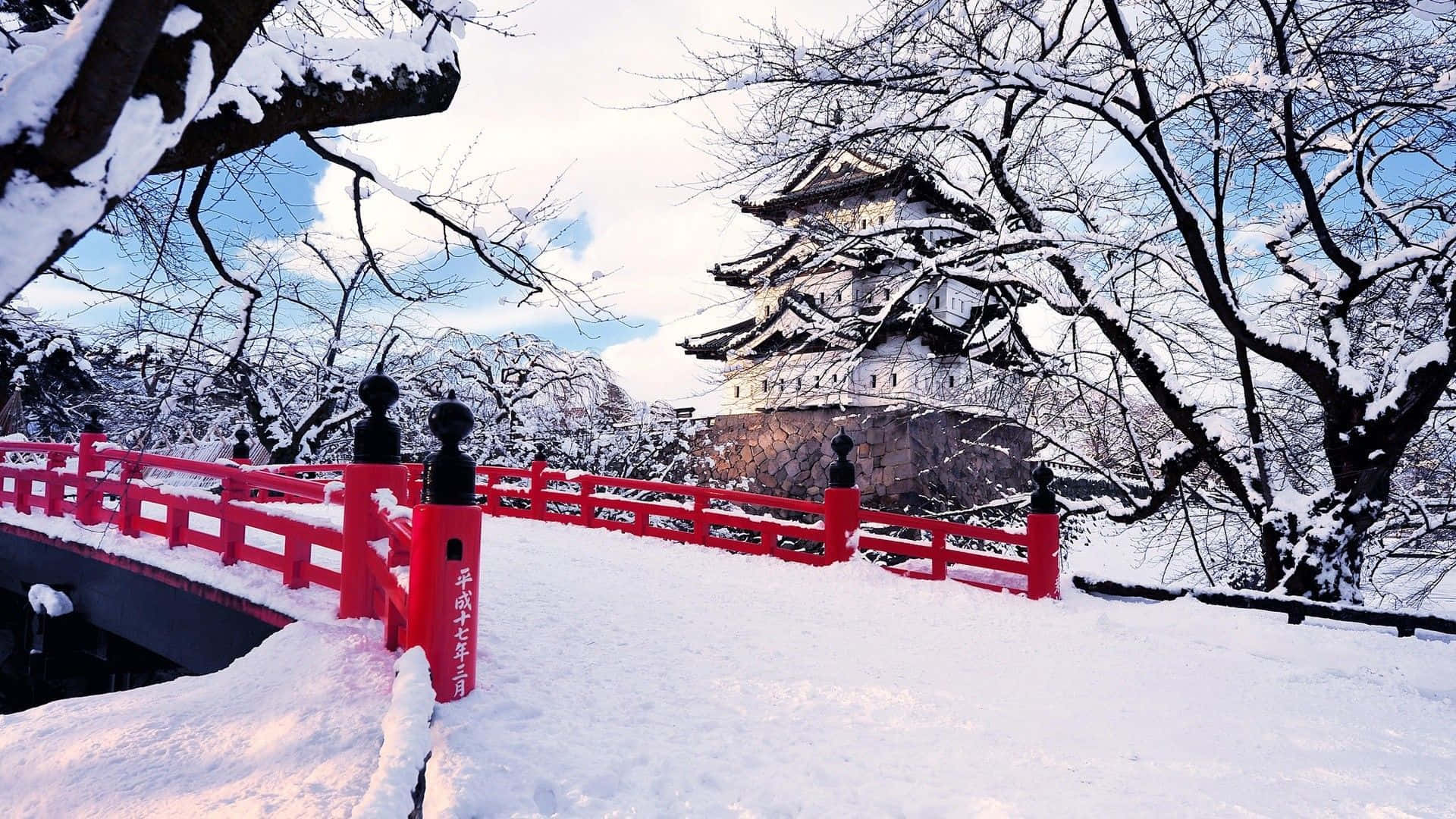 被雪覆蓋的紅色橋樑通往冬季的傳統日本城堡。