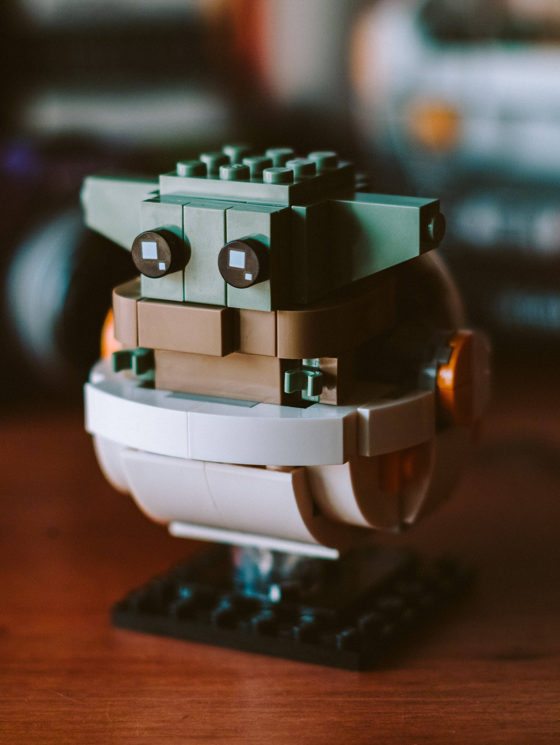 擁抱原力——星際大戰主題iPhone壁紙 壁紙 — 一個LEGO星際大戰古古迷你人偶的特寫，有大眼睛和綠色皮膚，坐在木質表面上。