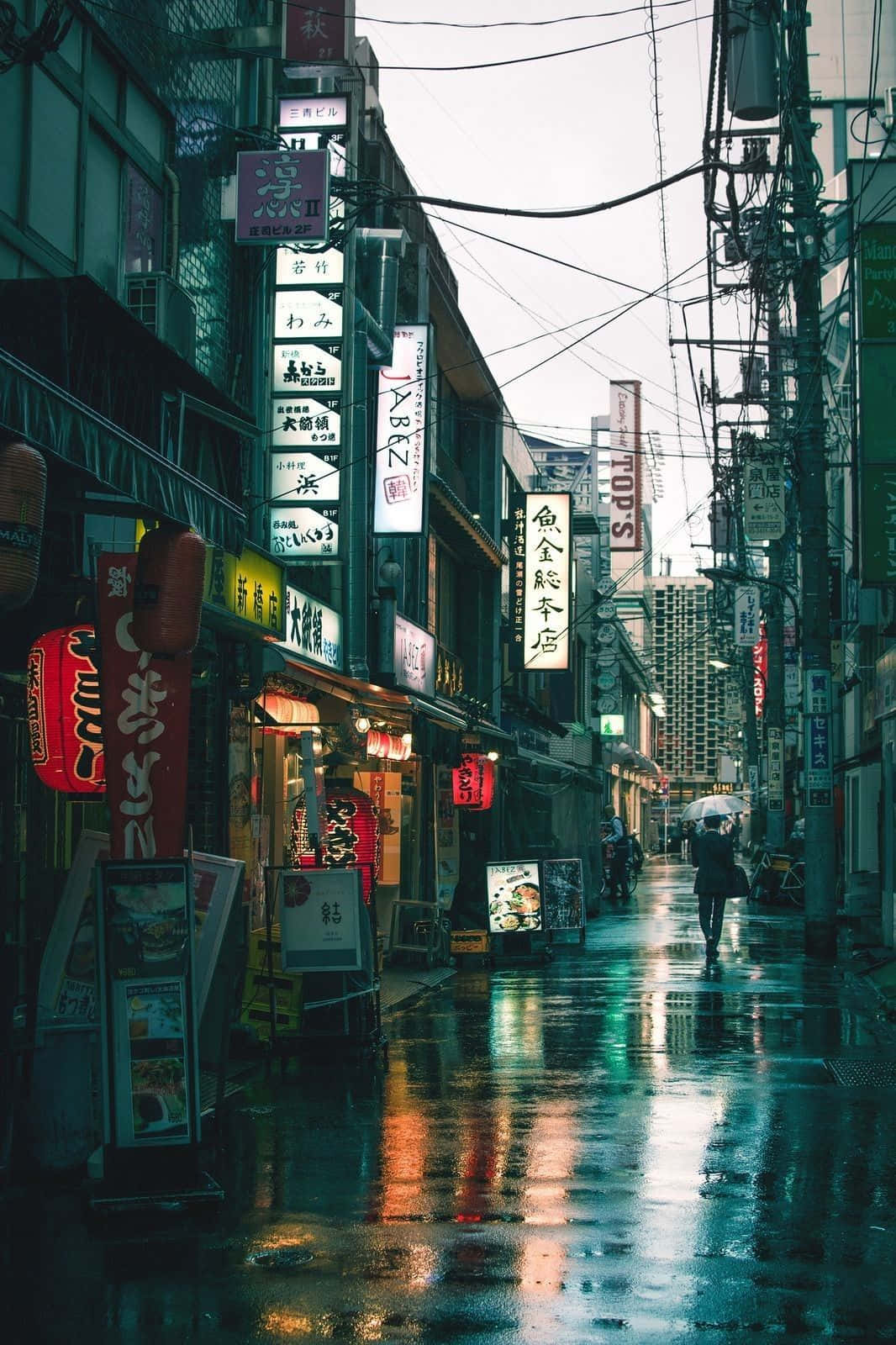 擁抱灰色美學的寧靜之美 壁紙 — 東京一條雨中的霓虹燈小巷，發光的招牌在濕漉漉的路面上反射，一個孤獨的身影正在走遠。