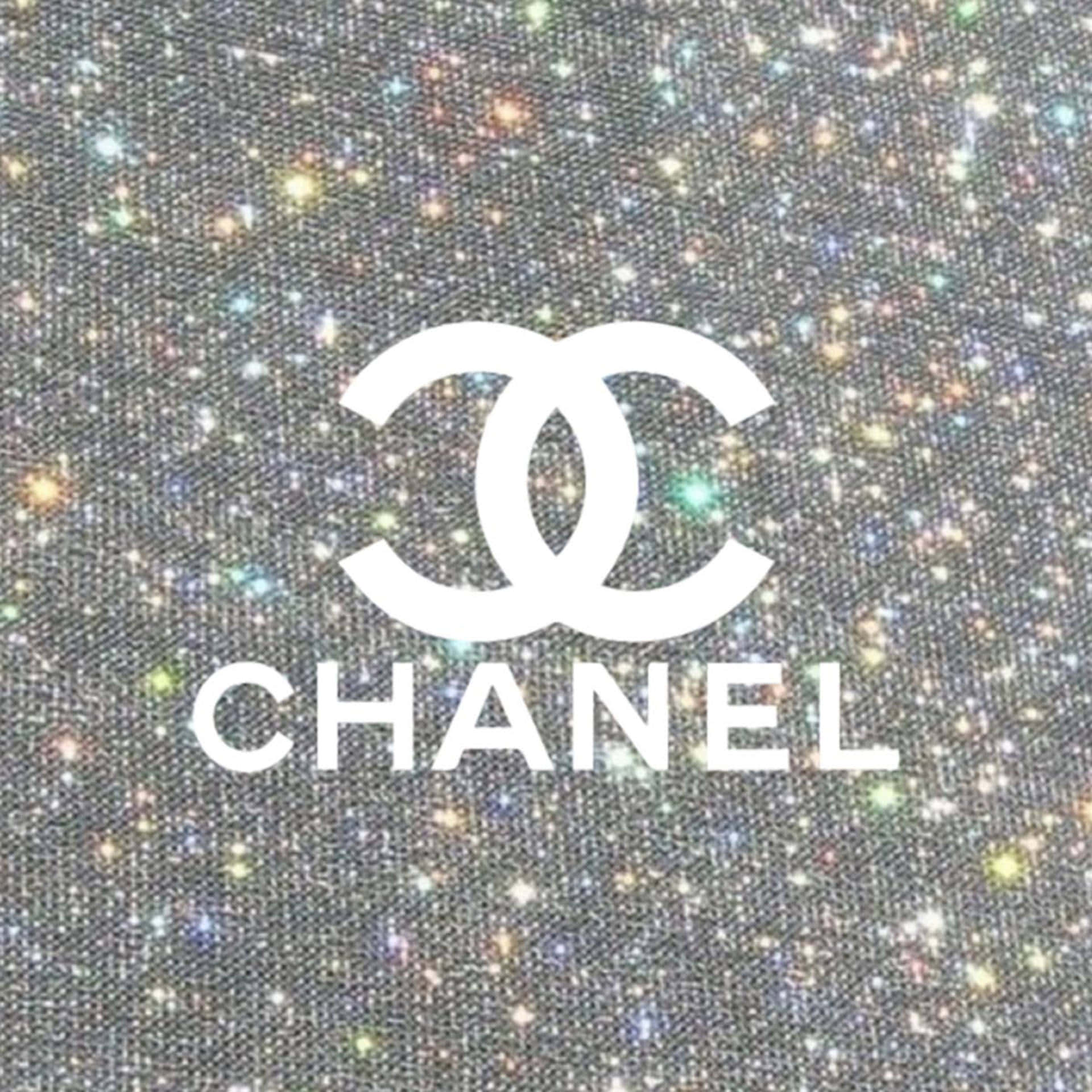 擁抱香奈兒的奢華 壁紙 — 白色Chanel標誌居中於閃爍銀色布料背景上，帶有多彩閃光。