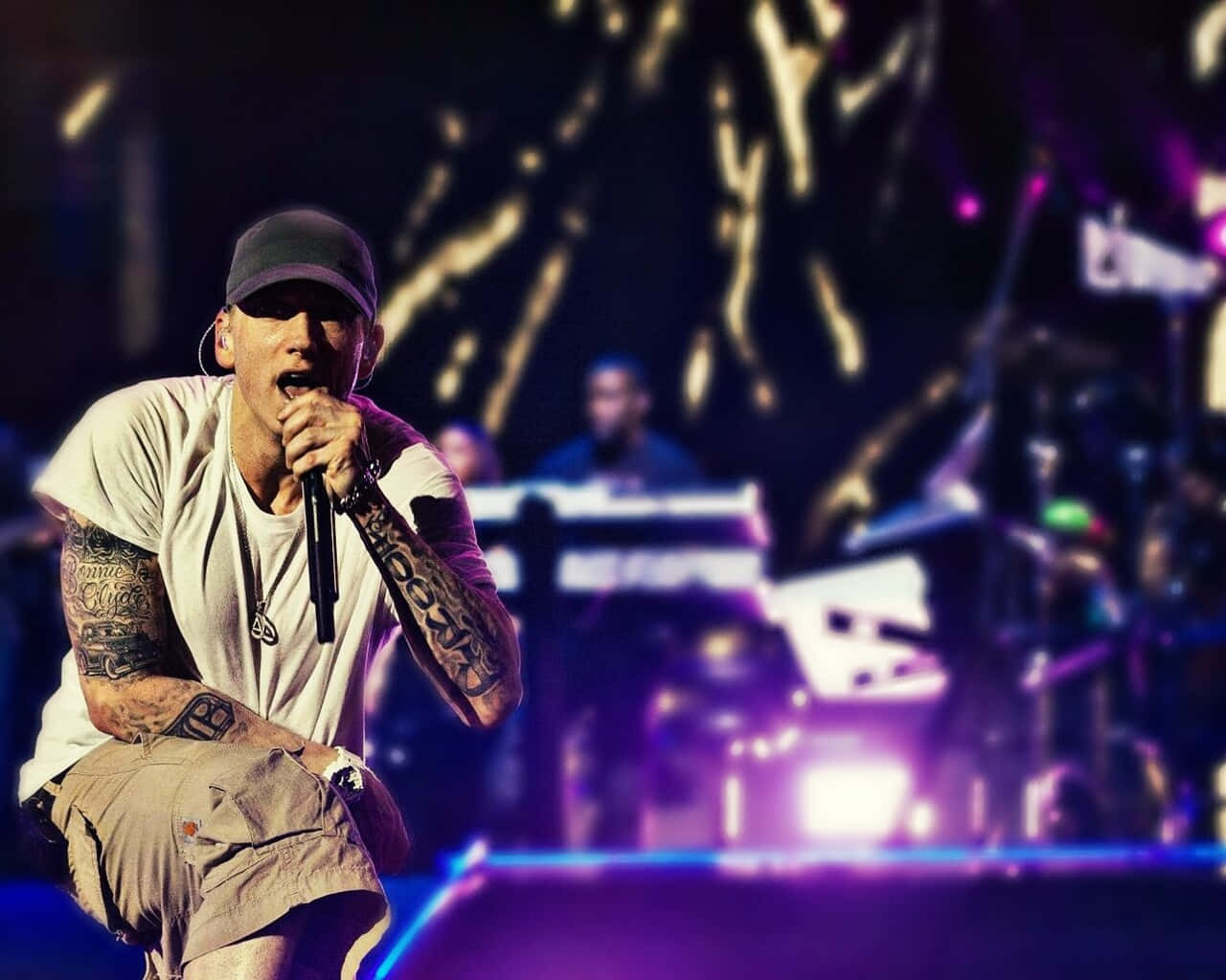 Eminem 桌布 壁紙 — 擁有紋身手臂的饒舌歌手在充滿活力的紫色和金色舞台燈光下，對著麥克風熱情表演。
