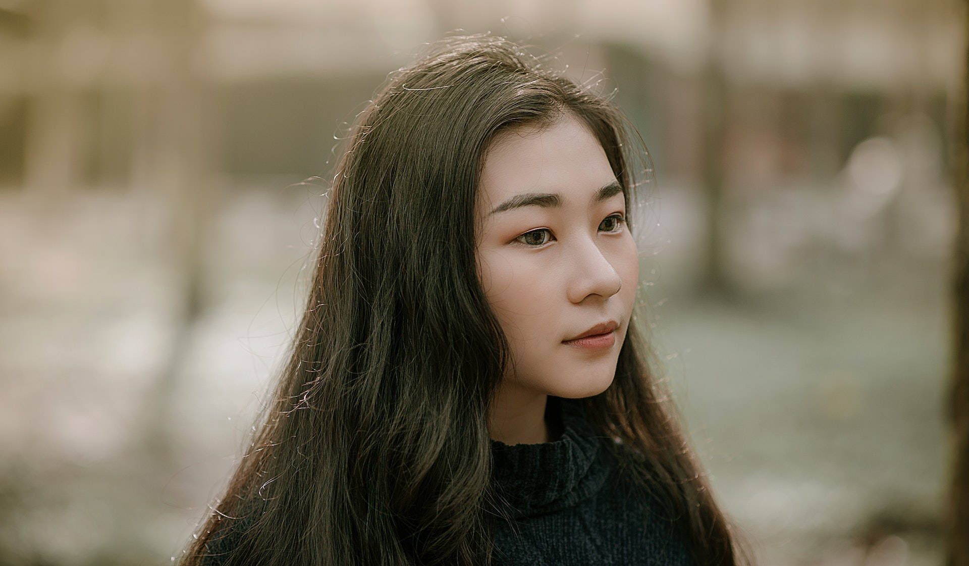 長黑髮的年輕女性在戶外若有所思地凝視。