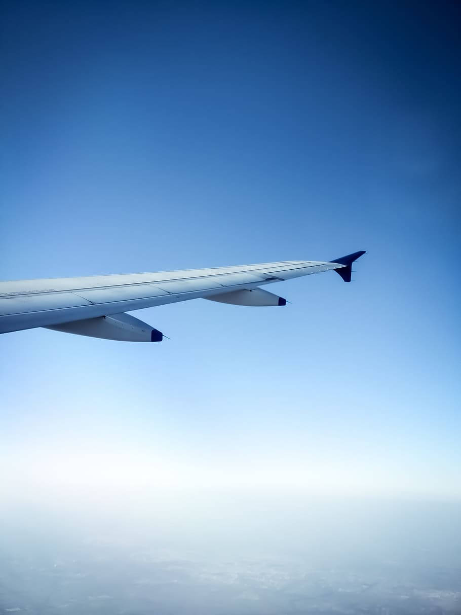 飛機機翼在清澈藍天中飛越雲層