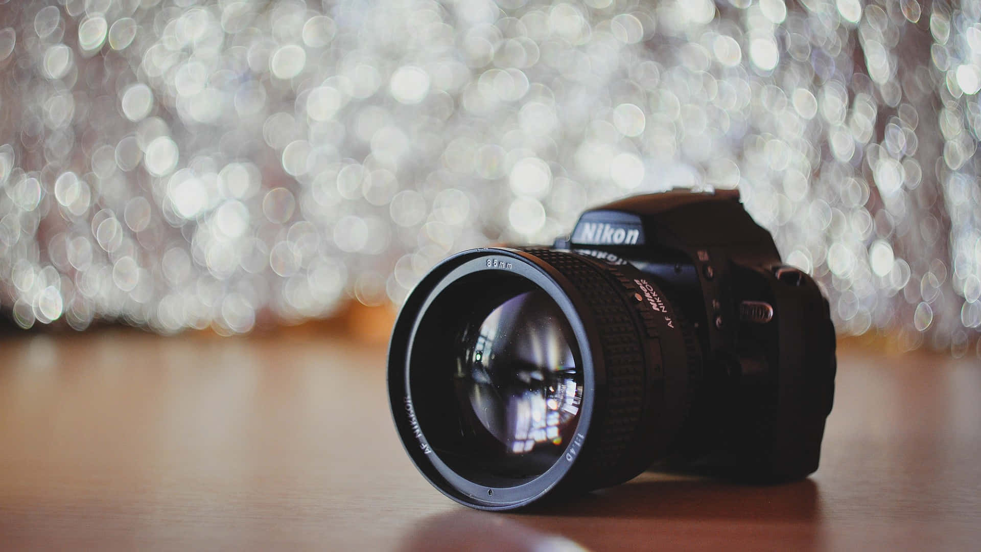 黑色 Nikon 相機在木頭上，背後有閃爍燈光