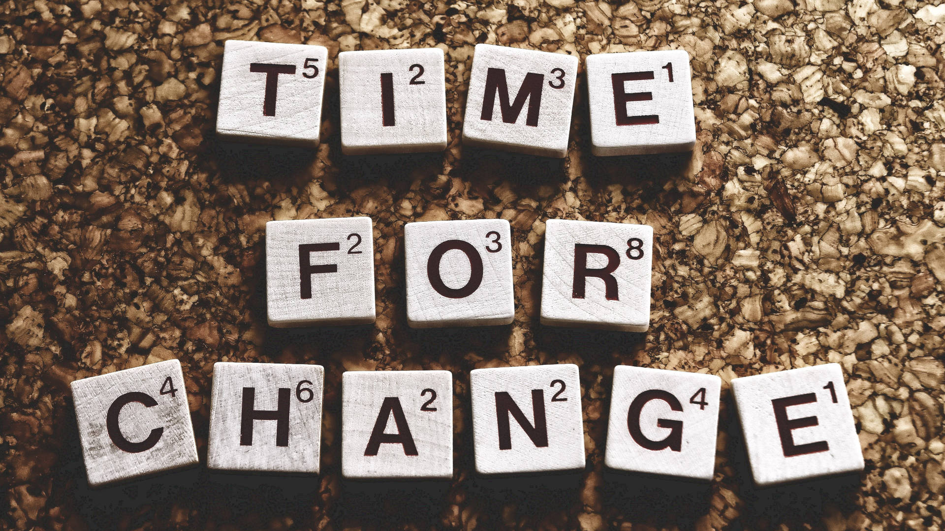 白色 Scrabble 字母磚在軟木背景上拼出 time for change。