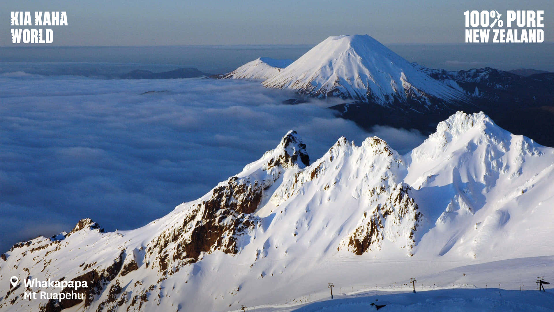 放大體驗雪覆大地的廣闊之美 壁紙 — 白雪覆蓋的魯阿佩胡山頂在雲海之上聳立，呈現清晰的冬季景觀。